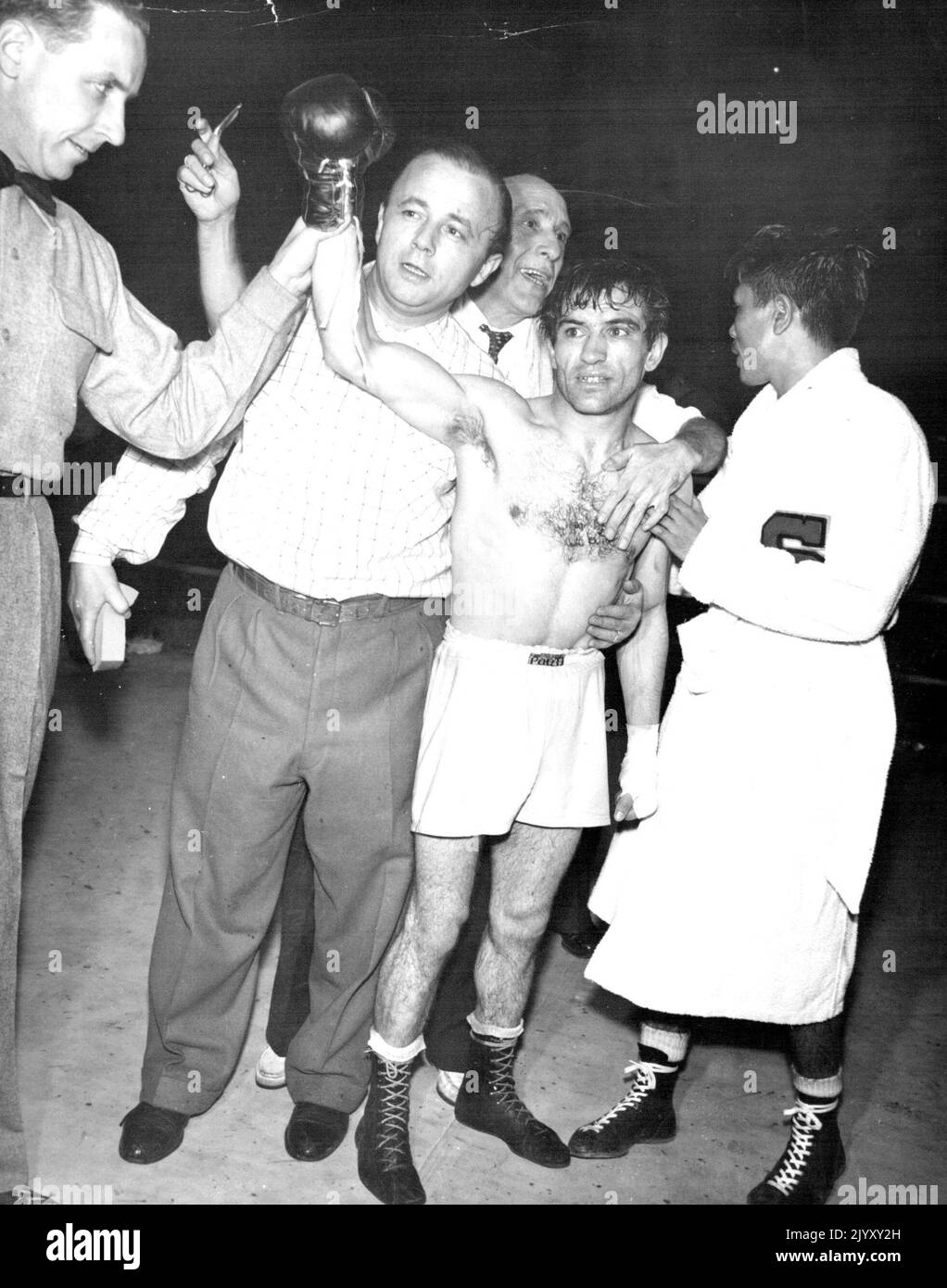 Neuer Flyweight-Champion -- der Argentinier Pascual Perez hat nach dem Sieg bei der Weltmeisterschaft im Fliegengewicht in einer einstimmigen Entscheidung über den japanischen Yoshio Shirai (rechts) in einem 15-Runden-Spiel in Tokio (26.. November) die Hand angehoben. Schiedsrichter Jack Sullivan (links) hält die Hand des Gewinners hoch, während Perez-Trainer, wie auch der Trainer von Perez, Frau Berger, und Manager Lozaro Kooi (zweiter von links) zugegen sind. 29. November 1954. (Foto von United Press Photo). Stockfoto