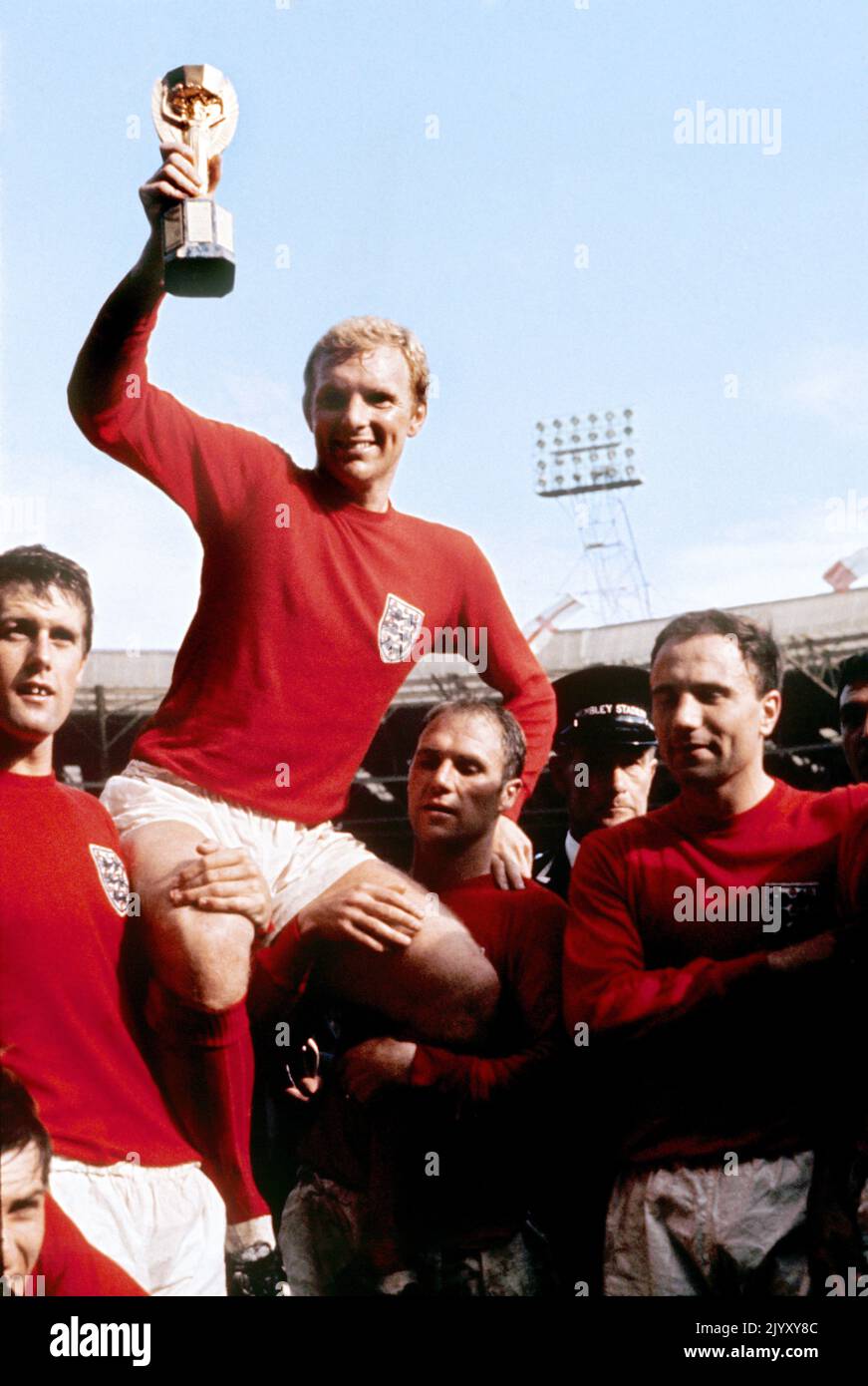 1966: Aktenfoto vom 1966. Juli von Englands Kapitän Bobby Moore, der von anderen Teammitgliedern getragen wird, als er die WM-Trophäe nach dem Sieg gegen Westdeutschland im Finale 4-2 in Wembley in London aushält. Ausgabedatum: Donnerstag, 8. September 2022. Stockfoto