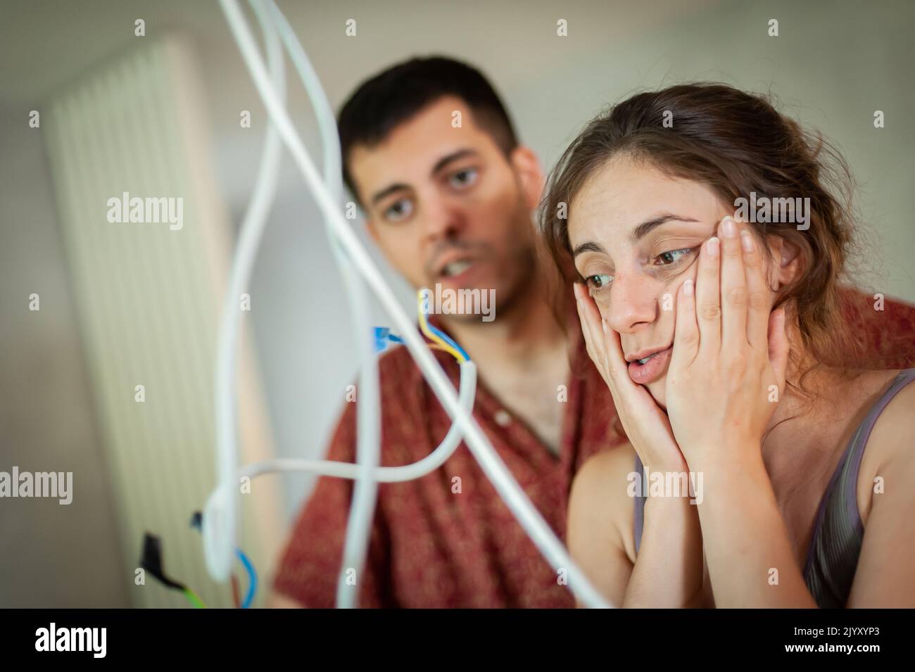 „Living Together“-Konzept, junge Männer und Frauen haben ein Problem mit elektrischen Kabeln von der Decke Stockfoto