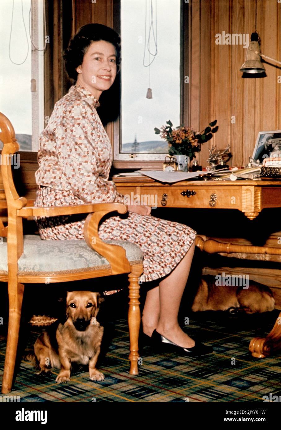 Aktenfoto vom 1/9/1972 von Königin Elizabeth II., die in ihrem Arbeitszimmer in Balmoral mit einem Hund unter ihrem Stuhl sitzt. Während ihrer Herrschaft besaß die Königin mehr als 30 Corgis, von denen viele direkte Nachkommen von Susan waren, die ihr 1944 als Geschenk zum 18.. Geburtstag von ihren Eltern geschenkt wurde und so geliebt wurde, dass sie Prinzessin Elizabeth auf ihren Flitterwochen begleitete. Ausgabedatum: Donnerstag, 8. September 2022. Stockfoto