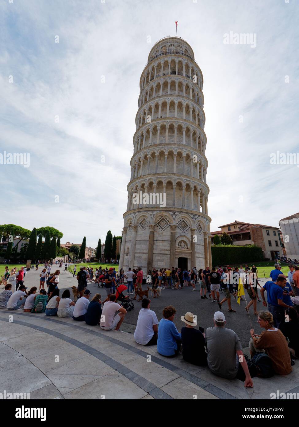 Platz der Wunder in Pisa, Toskana, Italien. Touristen sitzen am berühmten Schiefen Turm von Pisa. Stockfoto