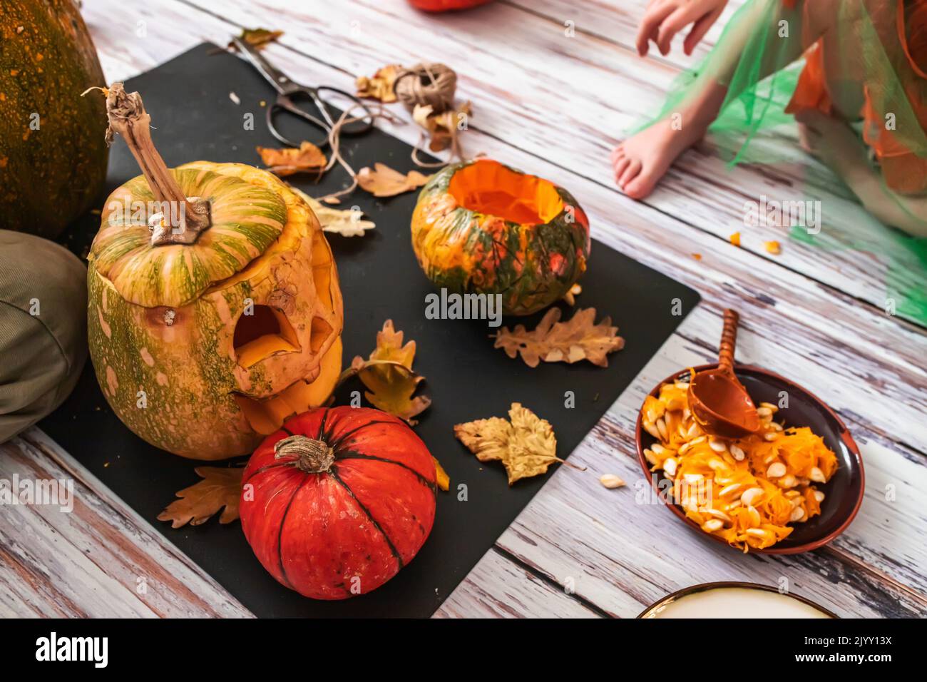 Die Familie sitzt auf dem Boden und bereitet sich auf Halloween vor. Die Kinder werden auf der Jack-o'-Laterne das gruselige Gesicht ausschneiden. Aus den Kürbissen Stockfoto
