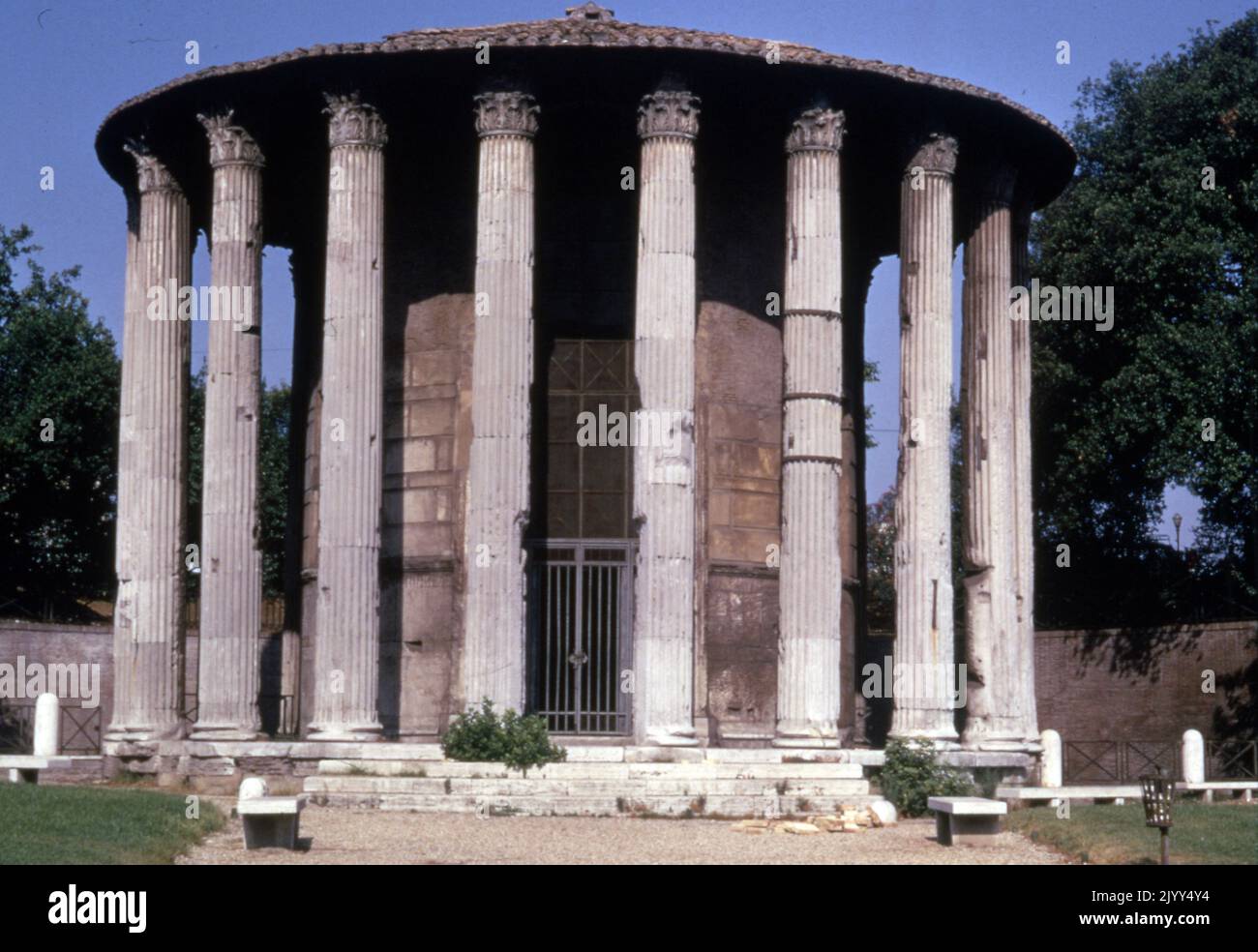 Der Vesta-Tempel, ein altes Gebäude in Rom, Italien, befindet sich im Forum Romanum in der Nähe der Regia und des Hauses der Vestaljungfrauen. Das bekannteste Merkmal des Tempels ist seine kreisförmige Grundfläche. Seit Beginn der Verehrung von Vesta in Privathäusern scheint die Architektur eine Erinnerung an ihre Geschichte zu sein. Der erhaltene Tempel verwendete griechische Architektur mit korinthischen Säulen, Marmor und einer zentralen Cella. Die verbleibende Struktur weist darauf hin, dass zwanzig korinthische Säulen auf einem Podium mit fünfzehn Metern Durchmesser errichtet wurden. Stockfoto