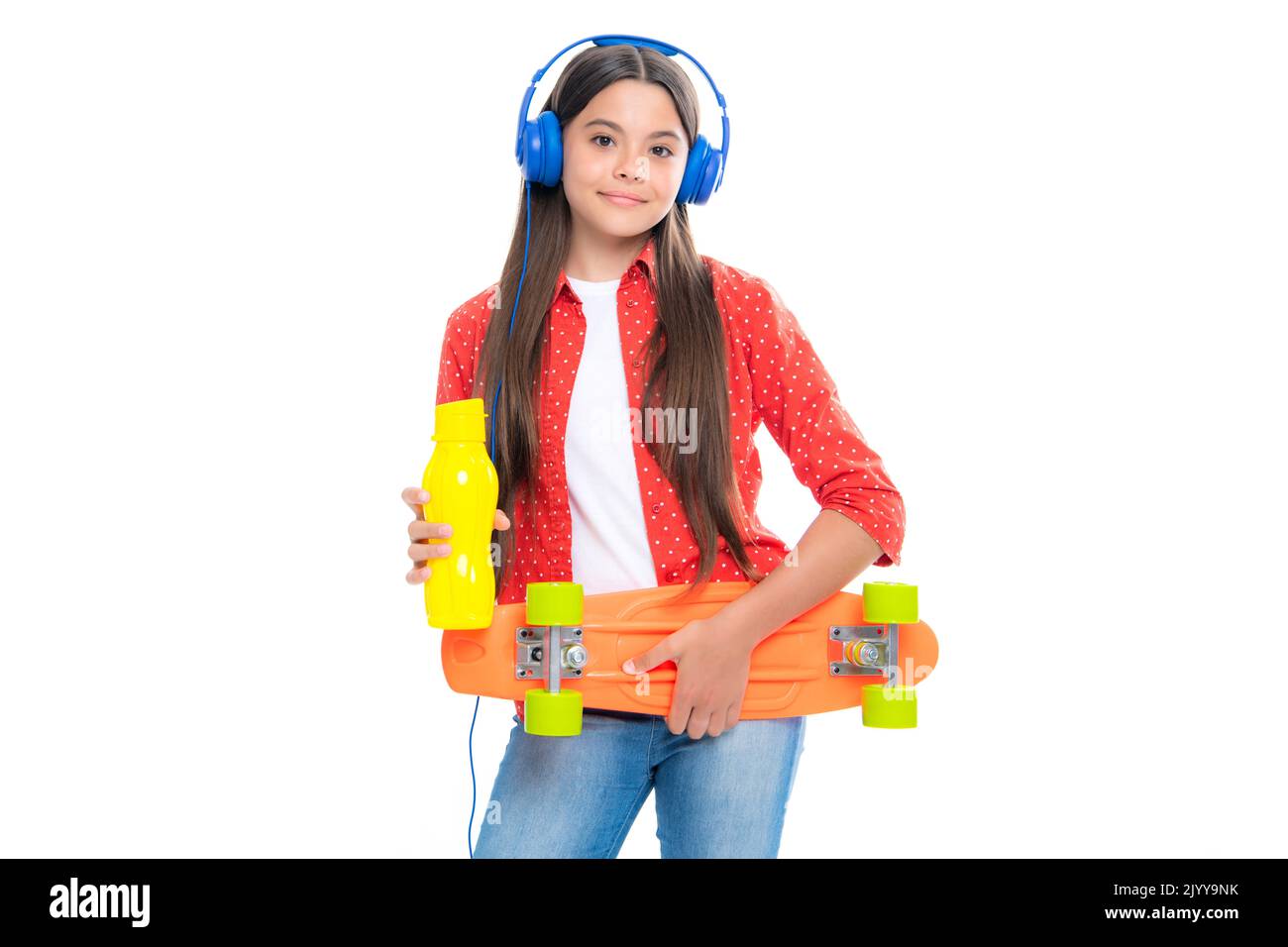 Teen girl 12, 13, 14 Jahre alt mit Skateboard Wasserflasche und Kopfhörer über Studio Hintergrund. Cooler moderner Teenager in stilvoller Kleidung. Teenager Stockfoto