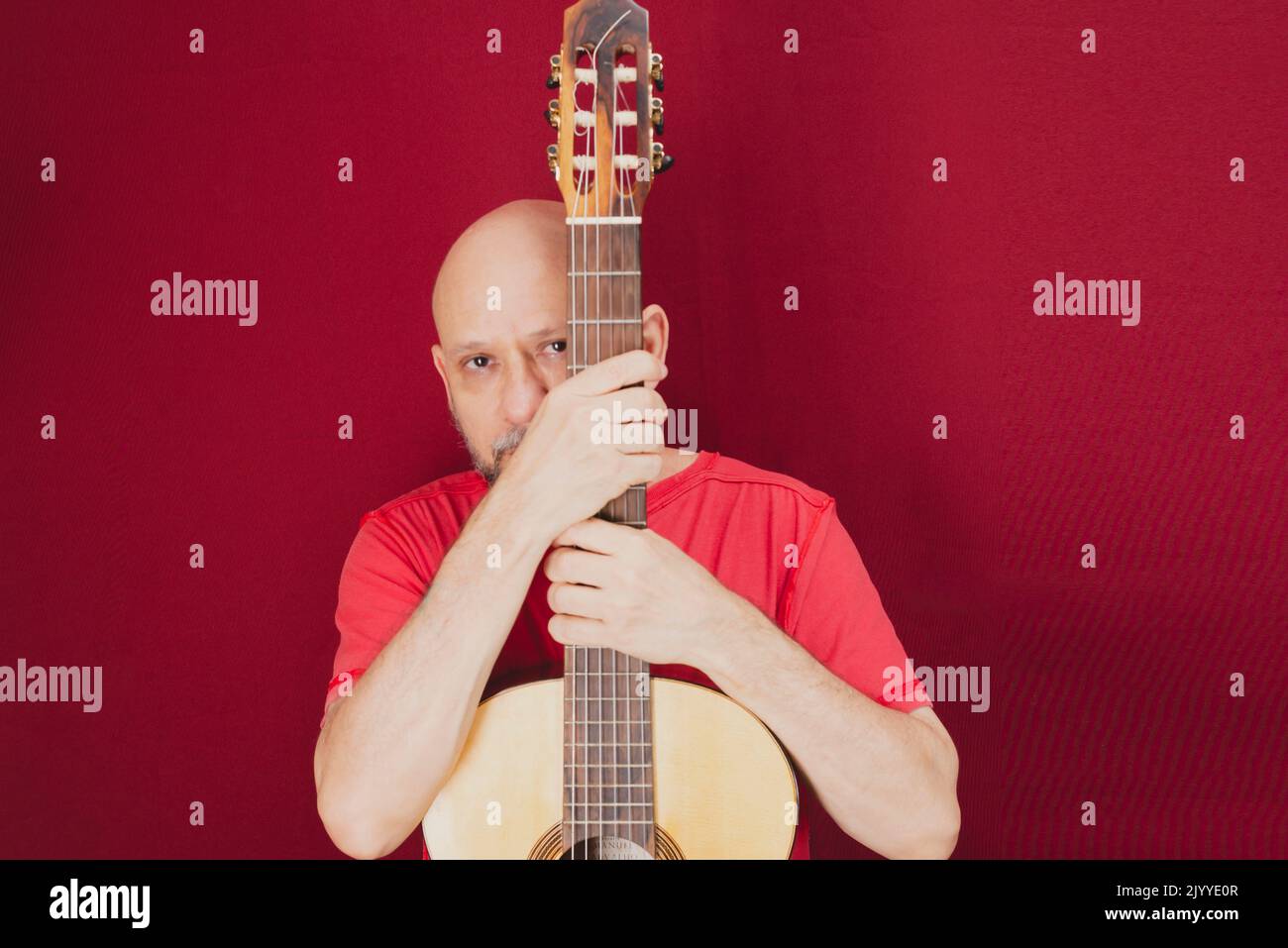 Saiteninstrument. Reifer charismatischer männlicher Gitarrist. Kerl mit Bart hält Gitarre. Bärtiger Mann in einem roten Hemd. Musik-Performer von Musik. Stockfoto