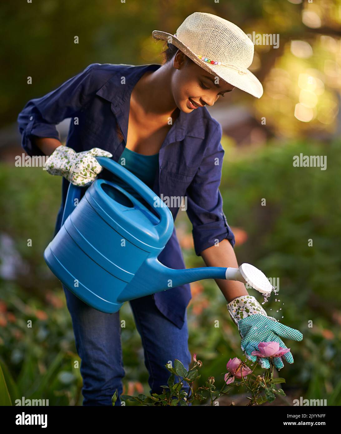 Die Arbeit in ihrem Garten ist eine Arbeit der Liebe. Eine junge Frau bewässert ihren Garten. Stockfoto