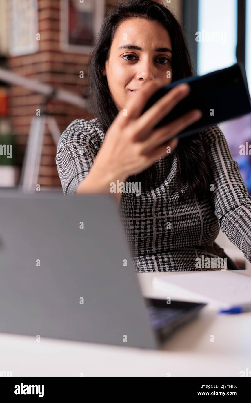 Junge Erwachsene, die mit dem Smartphone Fotos in der Arbeitspause machen und zu Hause eine Fernstartstelle machen. Mobiltelefon halten und Fotos machen, an Freiberuflern arbeiten und an Online-Lektionen teilnehmen. Stockfoto