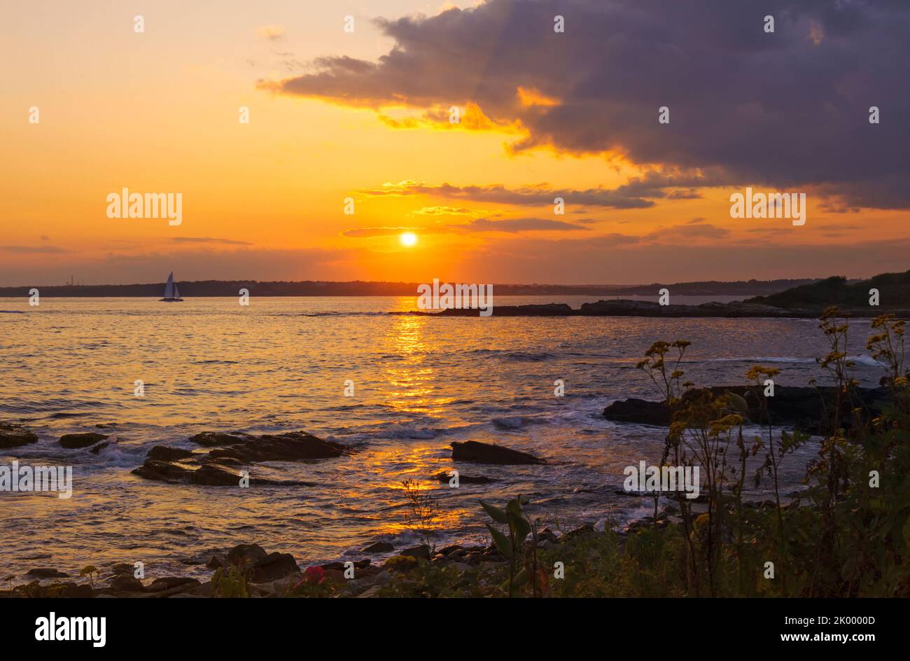 Seascape mit Gold und lila Sonnenuntergang, Segelboot, und Sonnenstrahlen in einem dramatischen Himmel, Newport, Rhode Island, Reise szenische Herbst Reise Kurzurlaub Landschaft. Stockfoto
