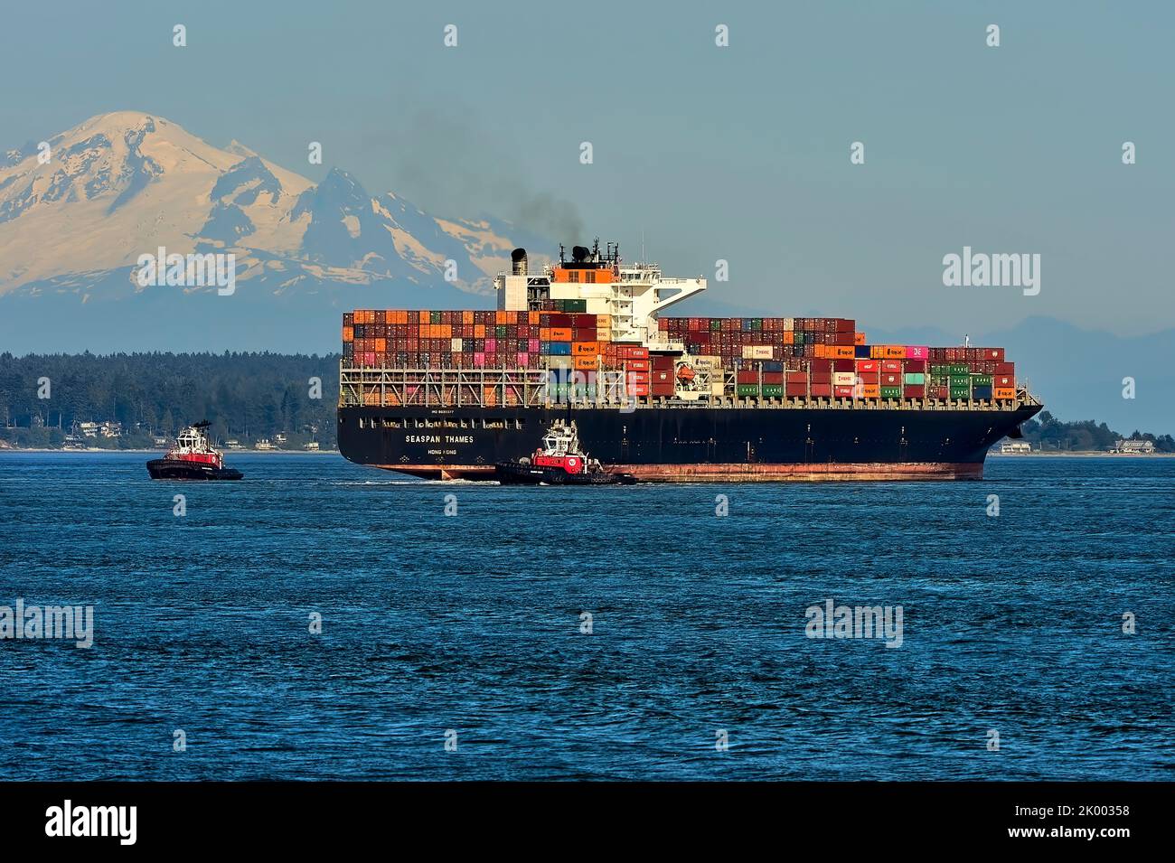 Ein Schiff mit einer Ladung Container wird von zwei Schleppbooten in den Hafen von Vancouver begleitet. British Columbia Canada. Stockfoto
