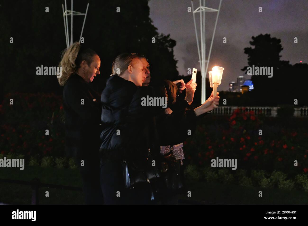 London, Großbritannien, 8.. September 2022. Drei Frauen fotografieren ihre Kerzen, die zur Erinnerung an Ihre Majestät, die Königin, angezündet werden, während Hunderte vor ihrem Londoner Wohnsitz, dem Buckingham Palace, ihren Respekt zollen, bis spät in den Abend, nachdem ihr Tod am frühen Abend angekündigt wurde. Das Land wird nun zehn Tage lang trauern, da die 70-jährige Regierungszeit des Monarchen zu Ende geht. Quelle: Elft Hour Photography/Alamy Live News Stockfoto