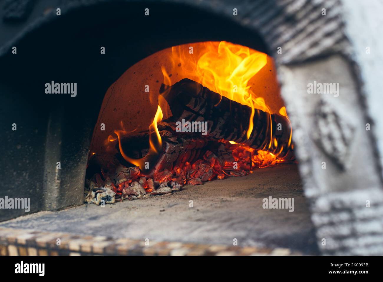 Holzofen mit Birkenstämmen zum Anzünden. Das Feuer brennt und der Ofen heizt sich auf. Vorderansicht. Stockfoto