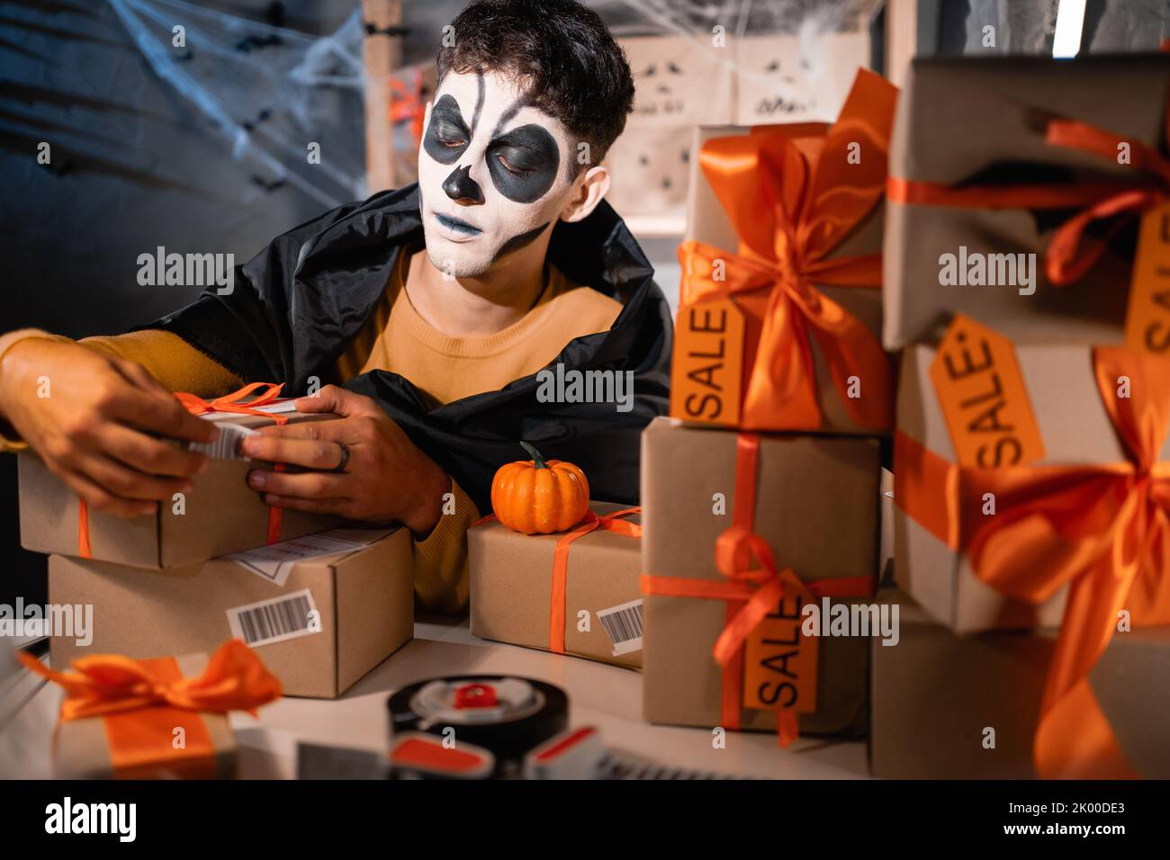 Drop-Versand Business-Besitzer trägt weißen Ton Schädel, professionelle Make-up im Home Office bereitet Ware für den Versand, klebt Barcode auf Box Stockfoto