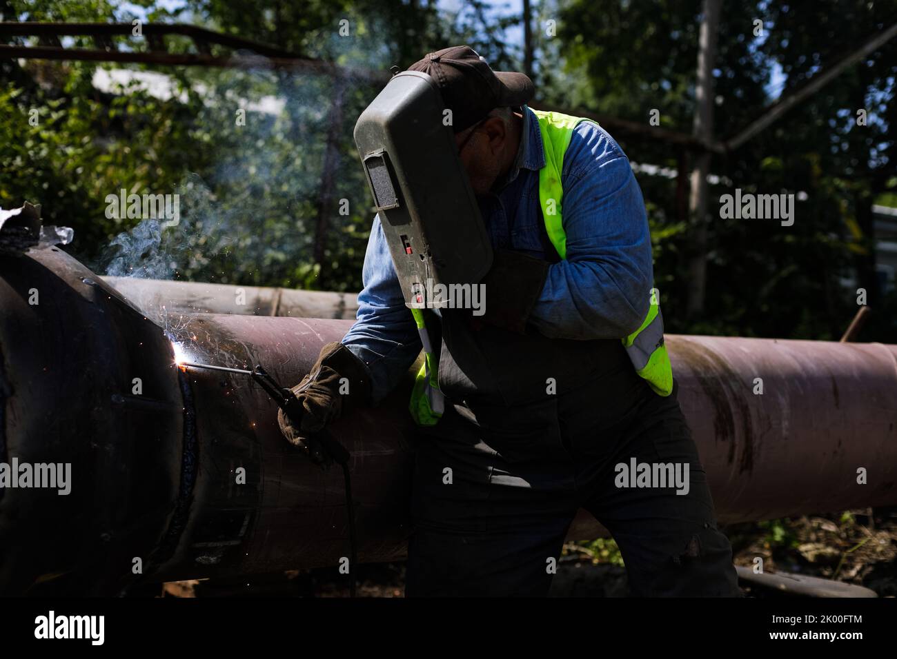 Details zur geringen Schärfentiefe (selektiver Fokus) mit einem professionellen Schweißer, der eine industrielle Metallrohrleitung schweißen kann. Stockfoto