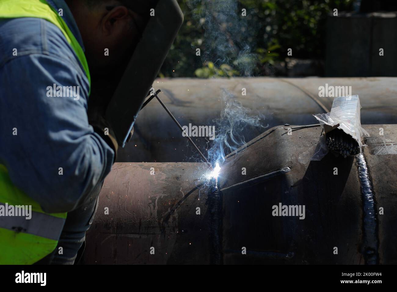 Details zur geringen Schärfentiefe (selektiver Fokus) mit einem professionellen Schweißer, der eine industrielle Metallrohrleitung schweißen kann. Stockfoto