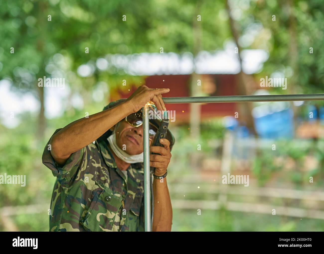 Ein Schweißer bei der Arbeit im Freien mit einem üppigen grünen Hintergrund. Stockfoto