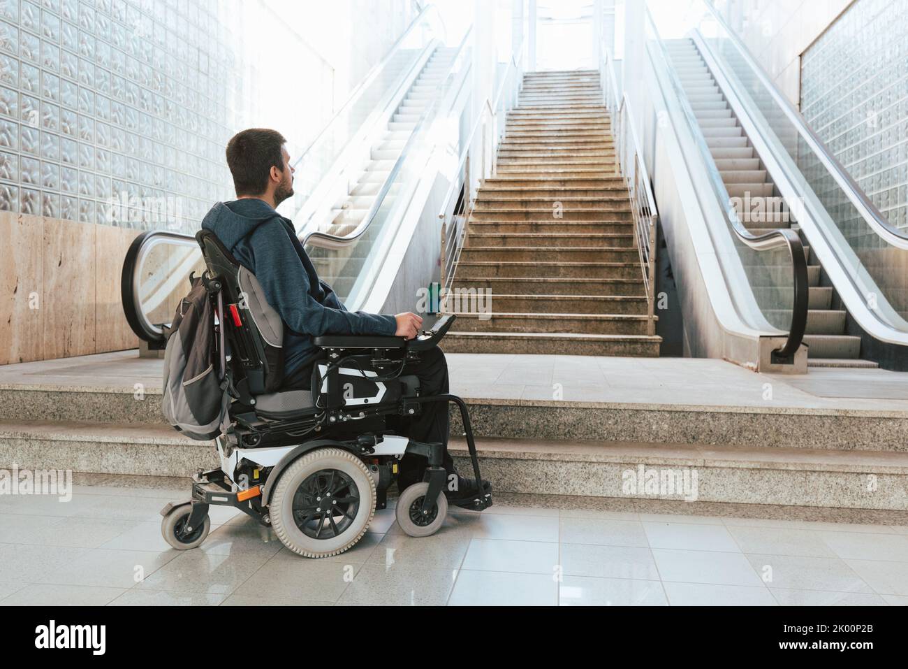 Ein Mann mit Behinderung im Rollstuhl hielt vor der Treppe an und machte sich auf architektonische Barrieren und Probleme mit der Zugänglichkeit aufmerksam Stockfoto