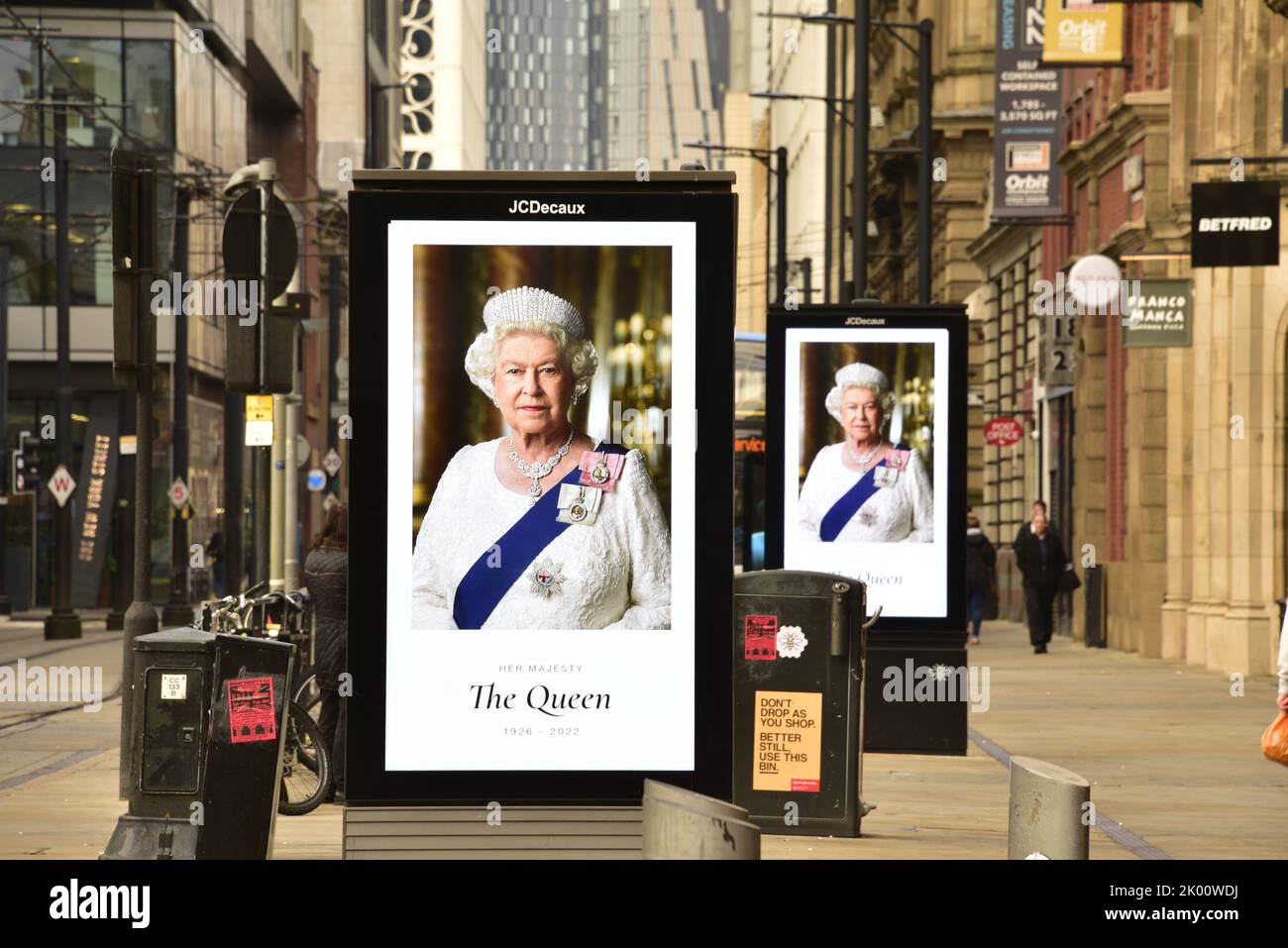 Manchester, Großbritannien, 9.. September 2022. Die Menschen gehen in Manchester, Großbritannien, an elektronischen Werbetafeln vorbei, auf denen Ihre Majestät, Königin Elizabeth II, zu sehen ist. Ihre Majestät, die Königin, starb im Alter von 96 Jahren am 8.. 2022. Der Stadtrat von Manchester hat auf seiner Website gesagt, dass die Stadt Manchester die offizielle 10-tägige Trauerperiode beobachten wird und dass: „Die Bewohner könnten Blumen zum Gedenken an den Tod Ihrer Majestät legen wollen. Am St. Ann's Square können Sie Blumen legen. Quelle: Terry Waller/Alamy Live News Stockfoto