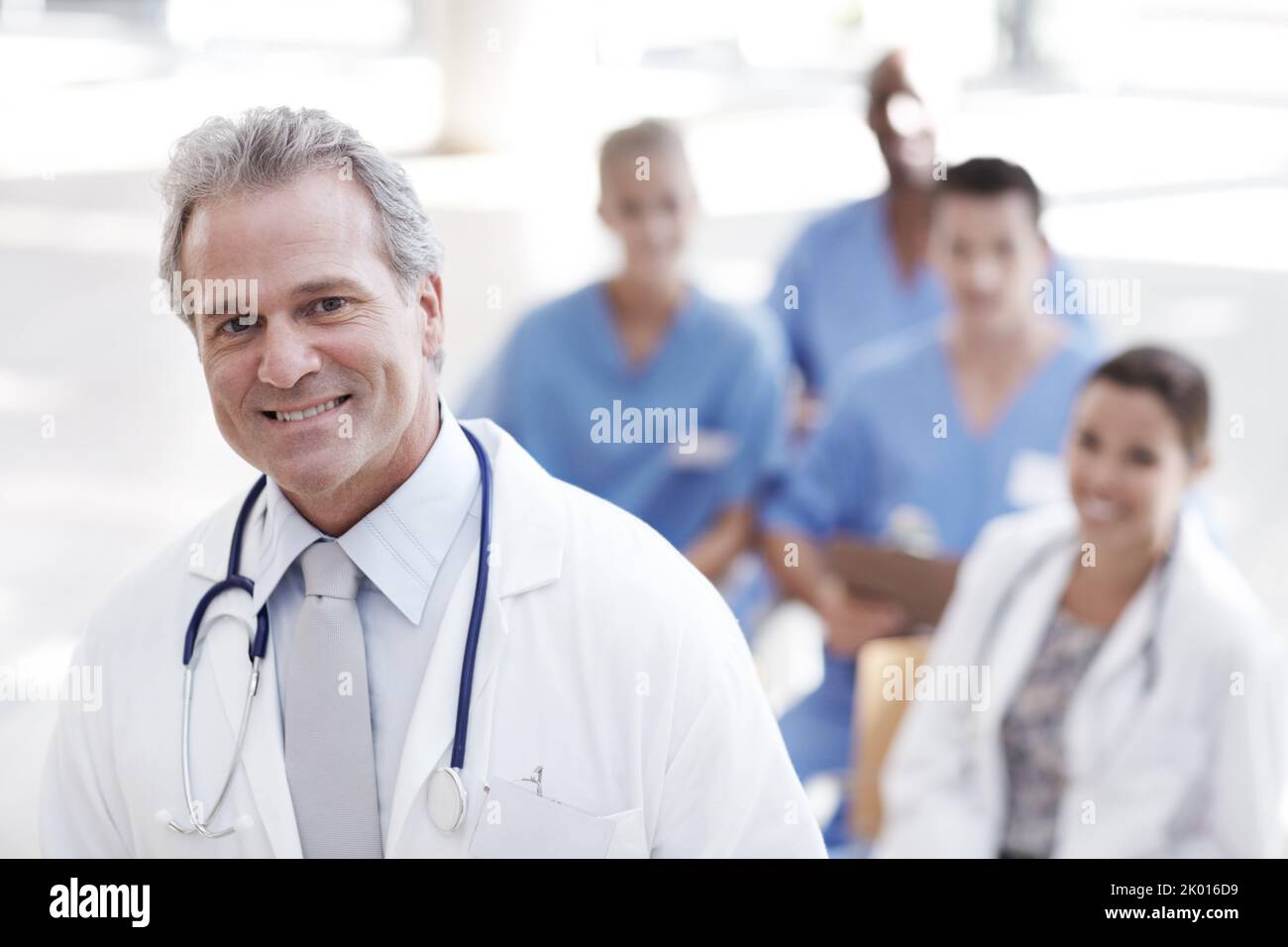 Medizinische Führungsposition. Ein Arzt steht mit Kollegen im Hintergrund. Stockfoto