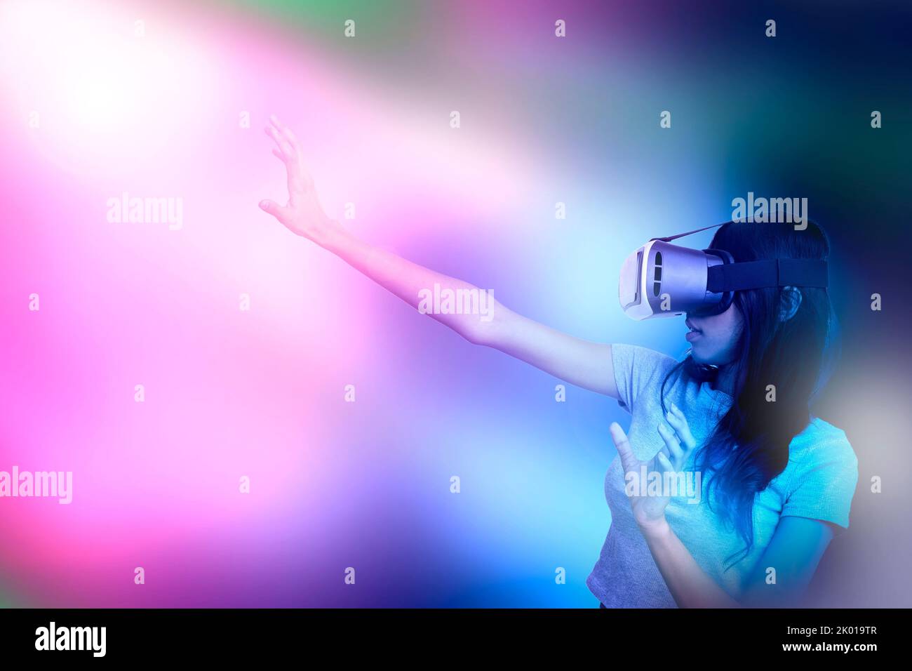 Frau mit 3D Gläsern, eingetaucht in die virtuelle Fantasie der meta-verse Traumwelt unter Lichtstrahl. Stockfoto