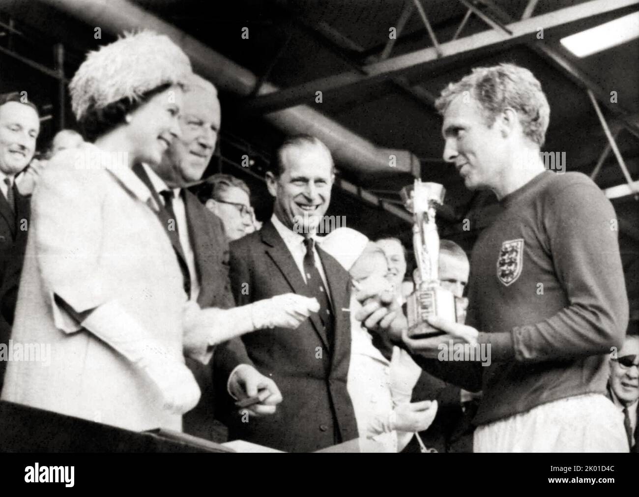 Queen Elizabeth II verleiht Sir Bobby Moore, Kapitän der 1966 im Wembley Stadium siegreichen englischen Fußballmannschaft, die Jules Rimet Trophy. Stockfoto