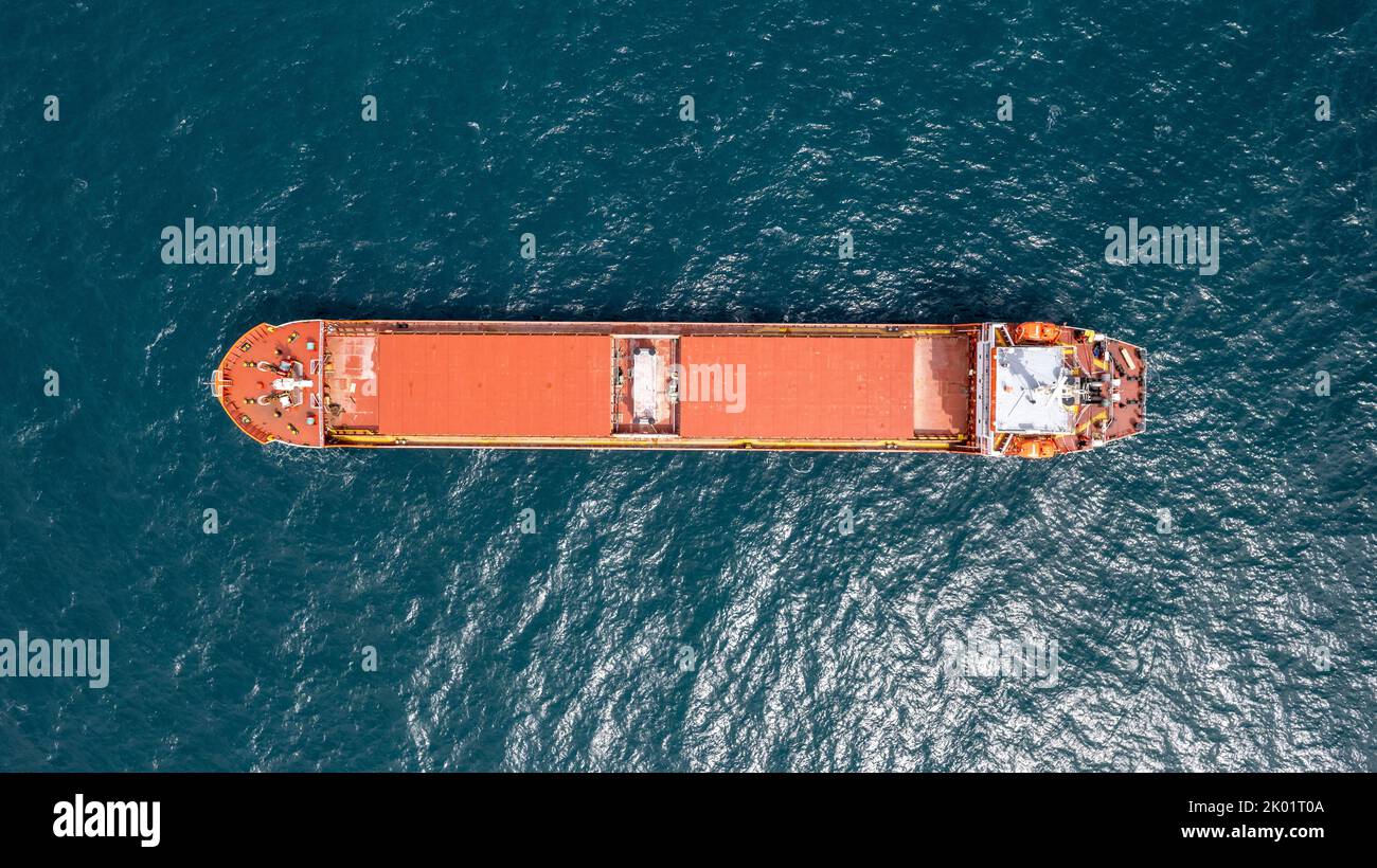 Unbeladenes rotes Frachtschiff, das in ruhigem Wasser verankert ist. Stockfoto