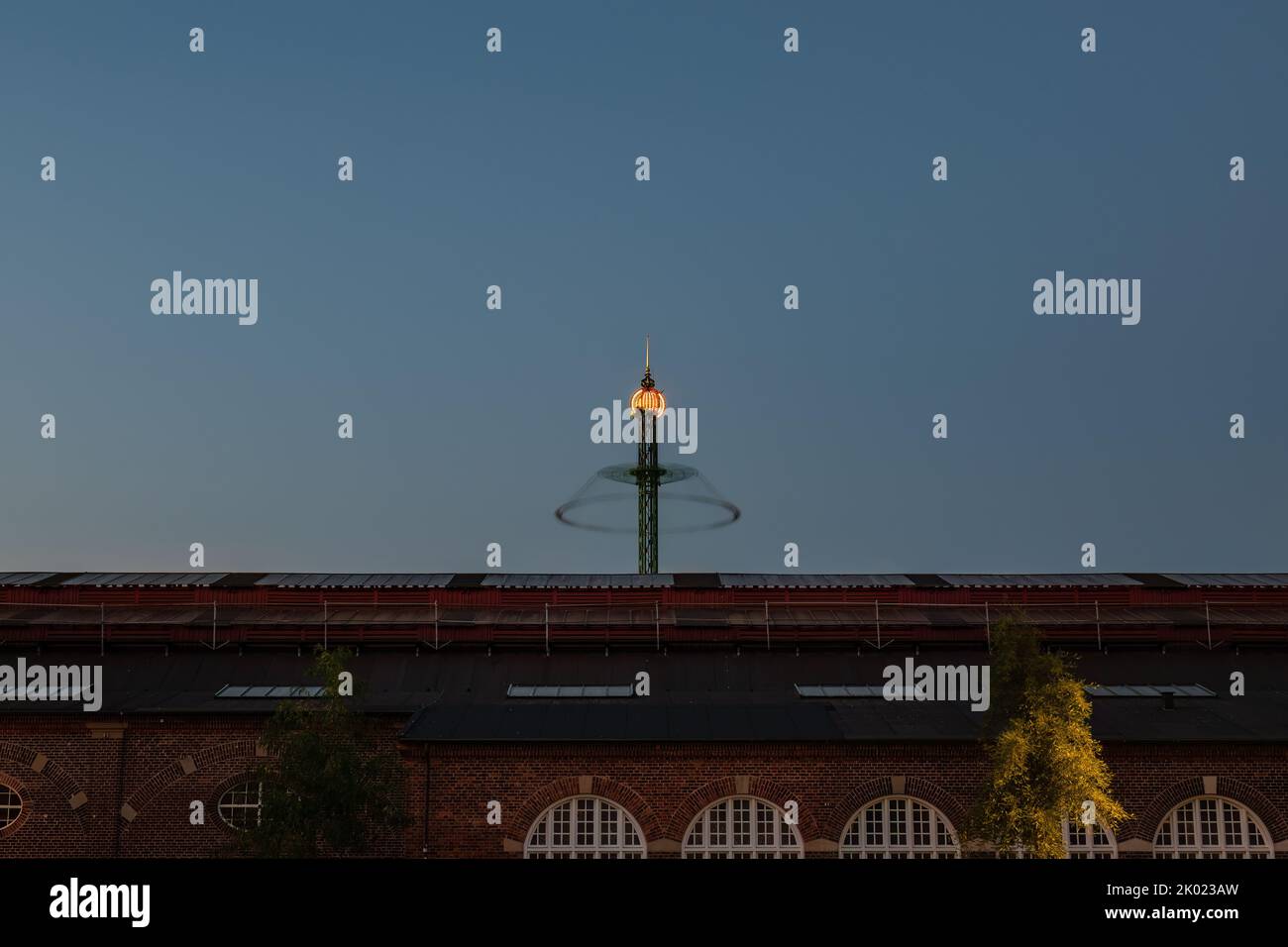 Kopenhagen, Dänemark. 13. August 2022. Langzeitaufnahme der Star Flyer-Vergnügungsfahrt in den Tivoli-Gärten, die sich gegen den späten Abendhimmel dreht Stockfoto