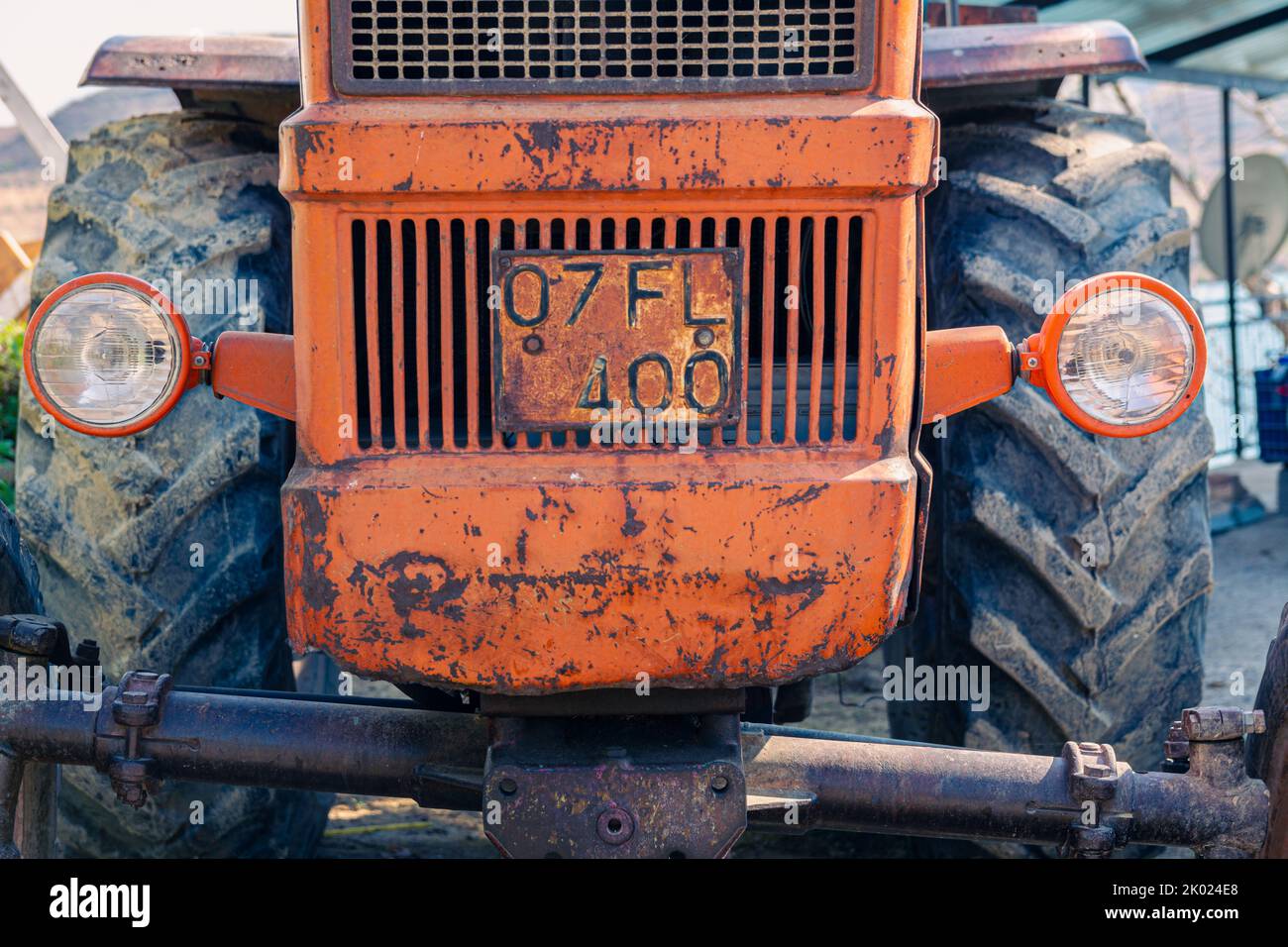 Alte rote Oldtimer-Traktor mit offenem Fahrerhaus. Foto eines ländlichen Traktors ohne Fahrerhaus. Nahaufnahme der Vorderseite des Traktors: Kühler, Scheinwerfer. Stockfoto