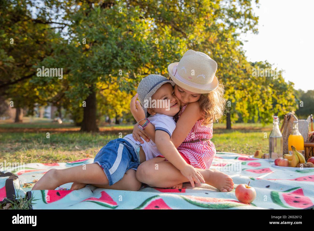 Zwei Geschwister umarmen sich während eines Picknicks in einem öffentlichen Park, Familienliebe Stockfoto