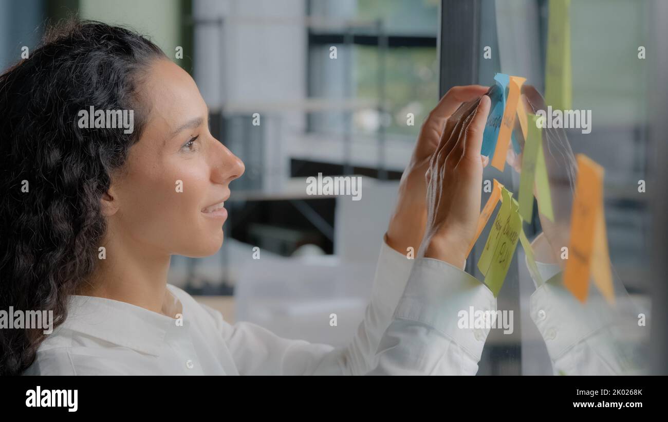 Seitenansicht lächelnd glücklich erfolgreiche Geschäftsfrau Notizen auf Sticker Schreiben Erinnerungen auf Farbe klebrig Label fröhlich weibliche Projektmanagerin Stockfoto