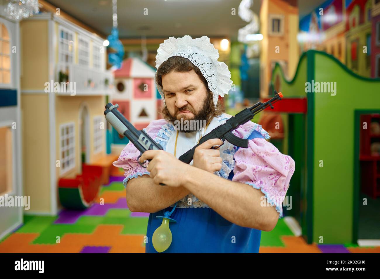 Lustige Baby Mann kriminellen posiert mit Spielzeug Waffe Stockfoto