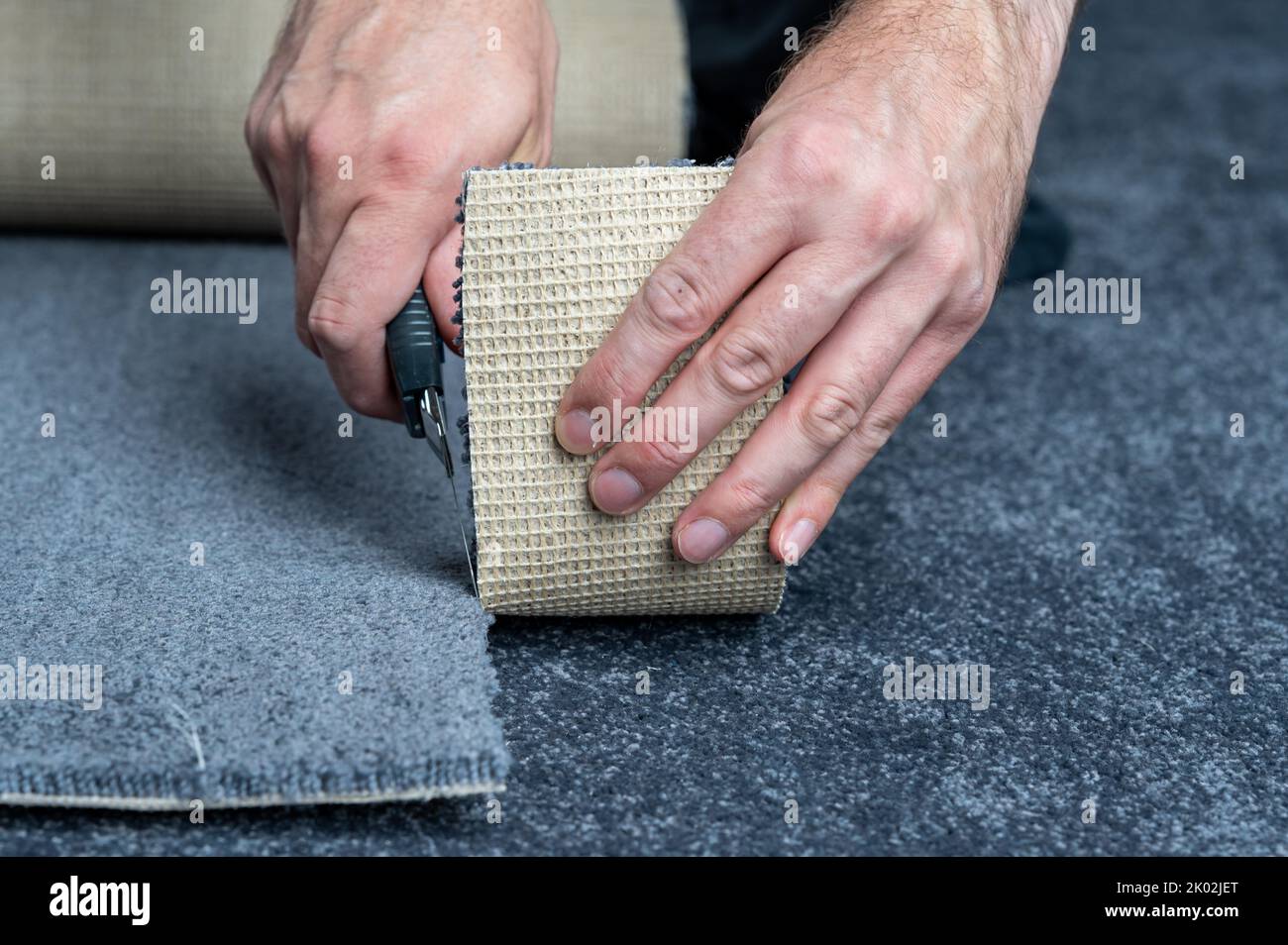 Handwerker schneidet einen neuen Teppich mit einem Teppichschneider. Stockfoto