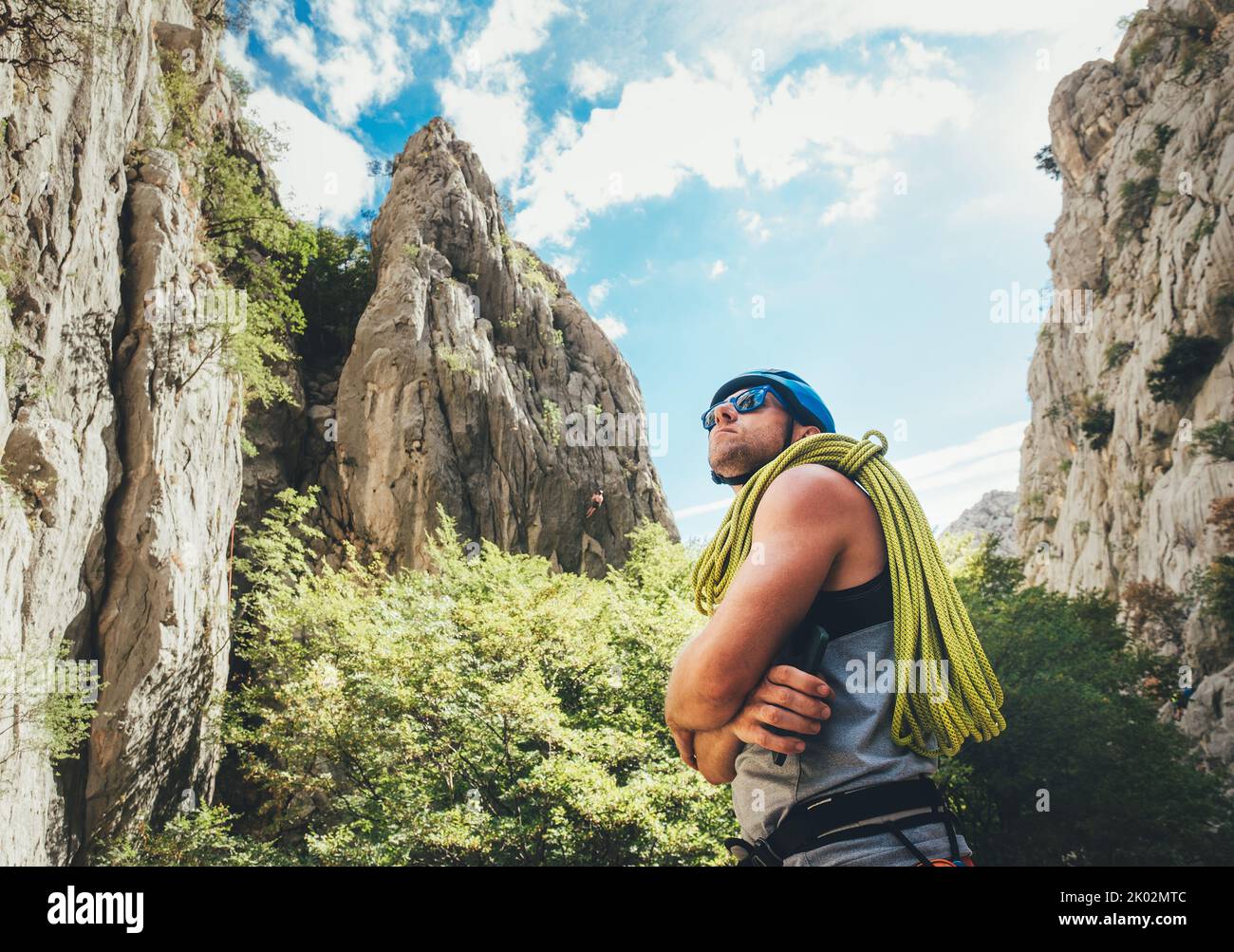 Kletterer Mann in Schutzhelm und Sonnenbrille mit Kletterseil auf der Schulter in der Paklenica Analyse Felswände für Klettern. Aktive pe Stockfoto