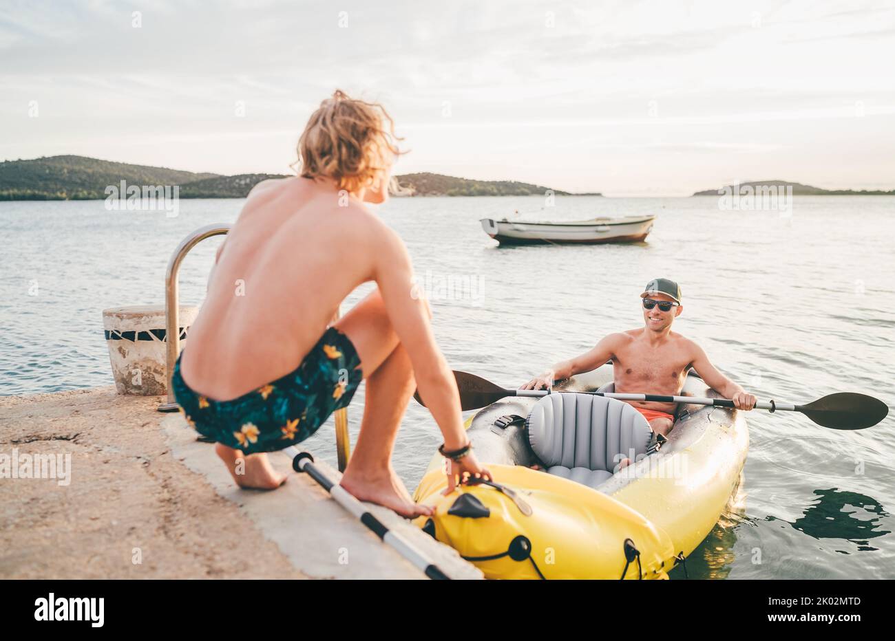 Vater mit Teenager-Sohn auf dem leuchtend gelben aufblasbaren Kajak, der von der Abendfahrt am Adriatischen Hafen in Kroatien in der Nähe von Sibeni zurückkehrt Stockfoto