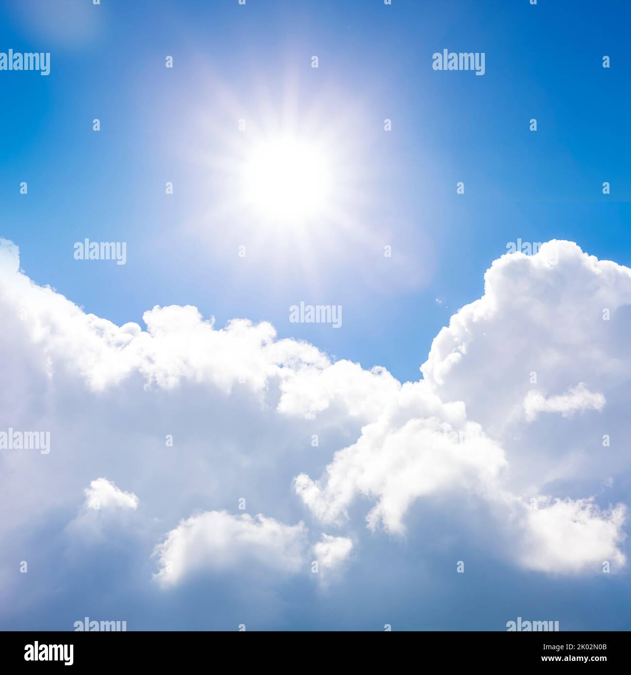 Sonne gegen blauen Himmel und weiße Kumuluswolken Stockfoto