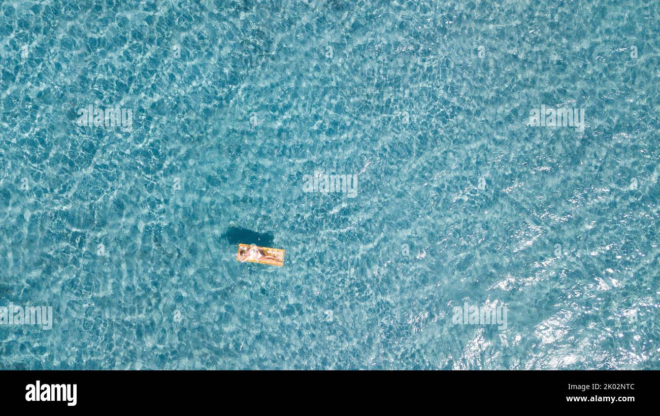 Frau schwimmt auf lilo aufblasbare Matratze über blau transparente Wasseroberfläche im Sommerurlaub Urlaub Freizeit-Aktivität. Weibliche Touristen haben sich auf dem Meer entspannen. Menschen und Strand glücklicher Lebensstil Stockfoto