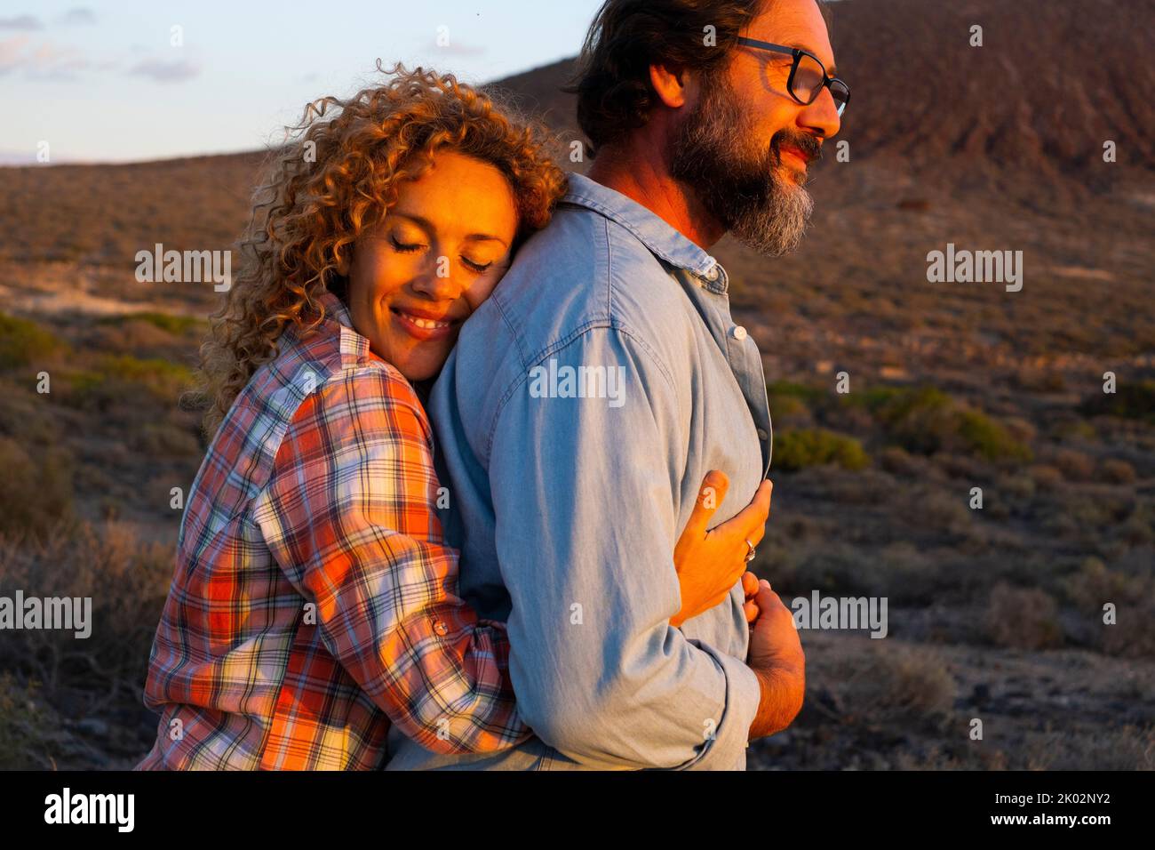 Ältere junge Menschen lieben es, sich zu umarmen und romantische Aktivitäten im Freien bei Sonnenuntergang zu genießen. Mann und Frau umarmen und lieben sich gegenseitig. Berge im Hintergrund. Reisekonzept Stockfoto