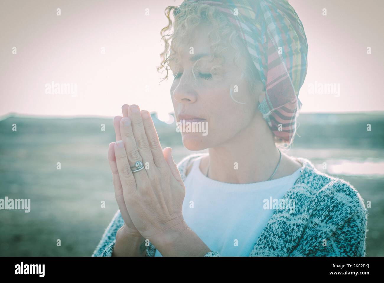 Nette Frau Seitenportrait mit Händen in Gebetsture für Wohlbefinden und Meditation Aktivität im Freien geklammt. Frieden und friedliche Menschen. Weibliches und inneres Lebensgleichgewicht. Blaue Stimmung Stockfoto