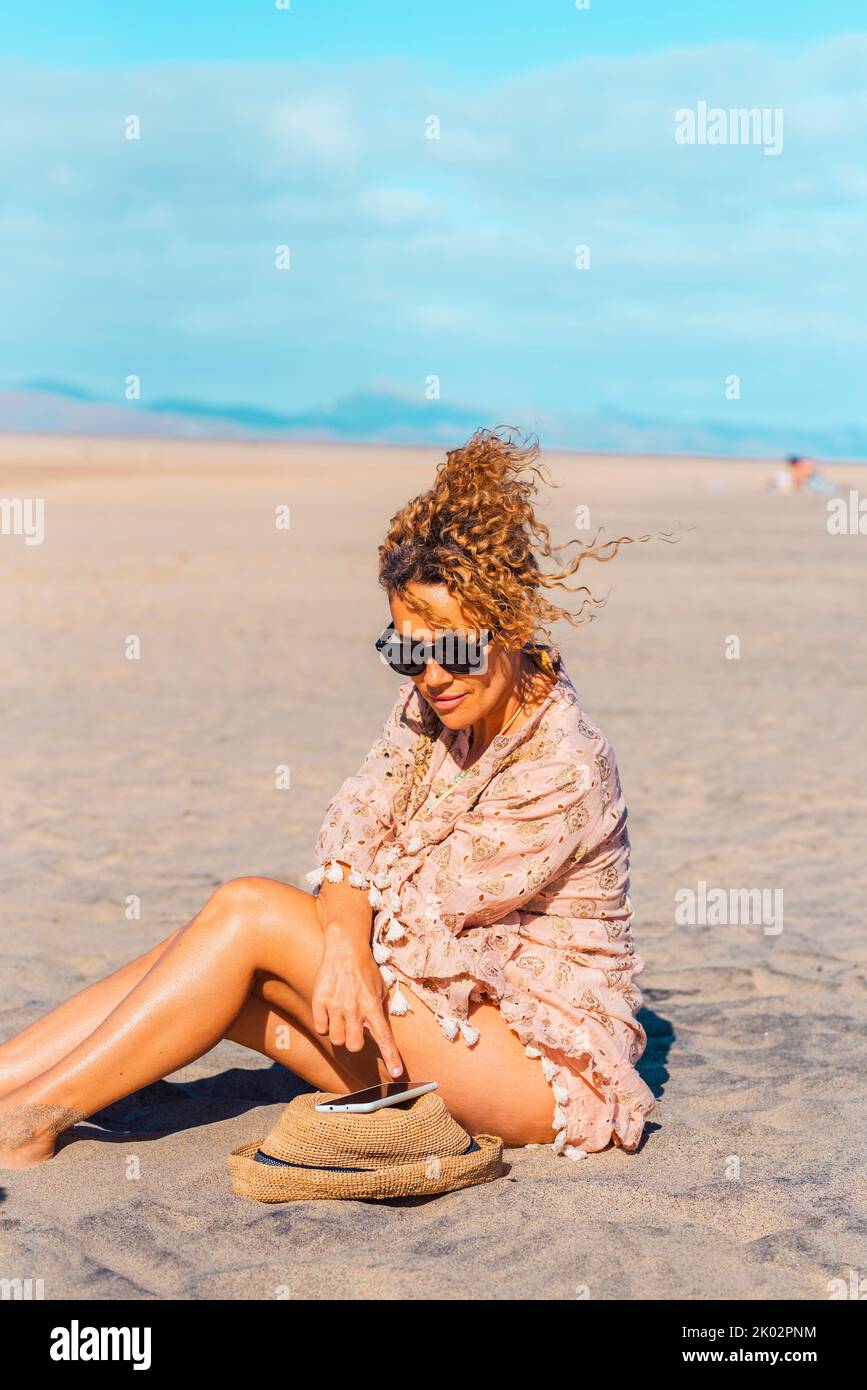 Weibliche Touristen entspannen unter der Sonne im Sommerurlaub Urlaubstag am Strand mit dem Handy. Attraktive Erwachsene Frau genießen die Verbindung im Freien. Freie alleinstehende Dame Menschen in Tourismus-Aktivität Stockfoto