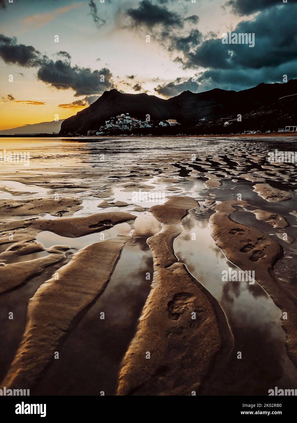 Grundansicht der erstaunlichen Strandlandschaft mit Sand und Meerwasser und tollen Farben beim Sonnenuntergang im Hintergrund. Konzept der Natur und Sommerurlaubsziel. Dramatischer Himmel Stockfoto