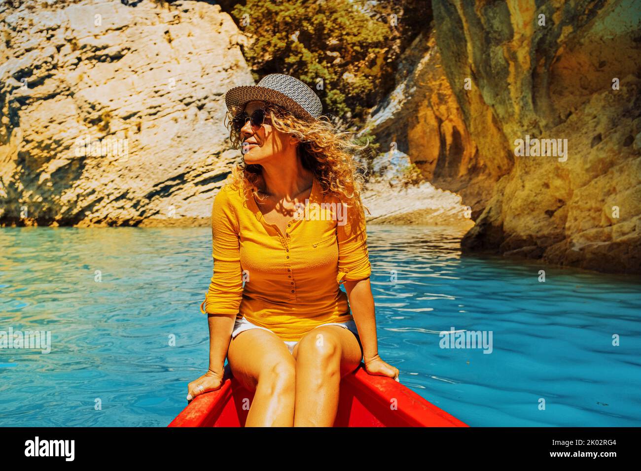 Fröhliche, attraktive Erwachsene Frau lächelt und genießt eine Kanujayaj-Reise auf einem blauen Fluss in einem Canyon. Touristen und Outdoor neue Freizeitaktivitäten. Sommerurlaub Urlaub Menschen Lebensstil Stockfoto