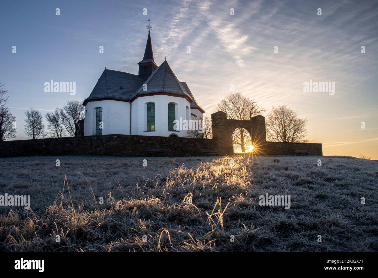 Deutschland, Hessen, Mittelhessen, Limburg-Weilburg, Taunus, Hintertaunus, Goldener Grund, Bad Camberg, Kreuzkapelle mit ersten Sonnenstrahlen am frostigen Wintermorgen ausgesetzt Stockfoto