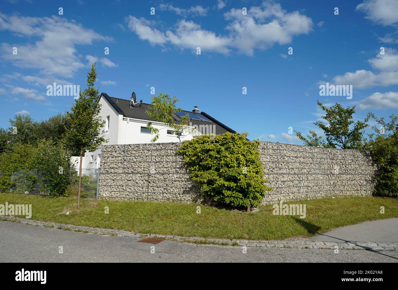 Deutschland, Bayern, Oberbayern, Altötting, Einfamilienhaus hinter hohem Gabionenzaun Stockfoto