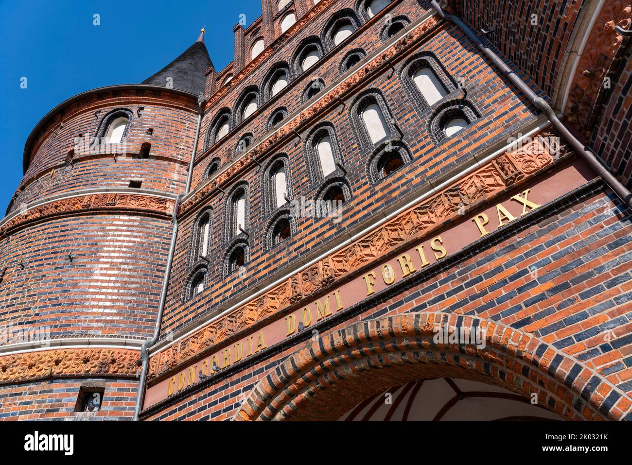 Das Holstentor ist das Wahrzeichen der Stadt und neben dem Burgtor das einzige erhaltene Stadttor Lübecks. In den Räumen des Holstentors befindet sich seit 1950 das Stadthistorische Museum. Das spätgotische Gebäude ist Teil der ehemaligen Lübecker Stadtbefestigung. Inschrift auf der Felsseite des Holsten-Tores. 'Concordia domi foris pax' 'Eintracht im Inneren und Frieden im Freien'. Stockfoto