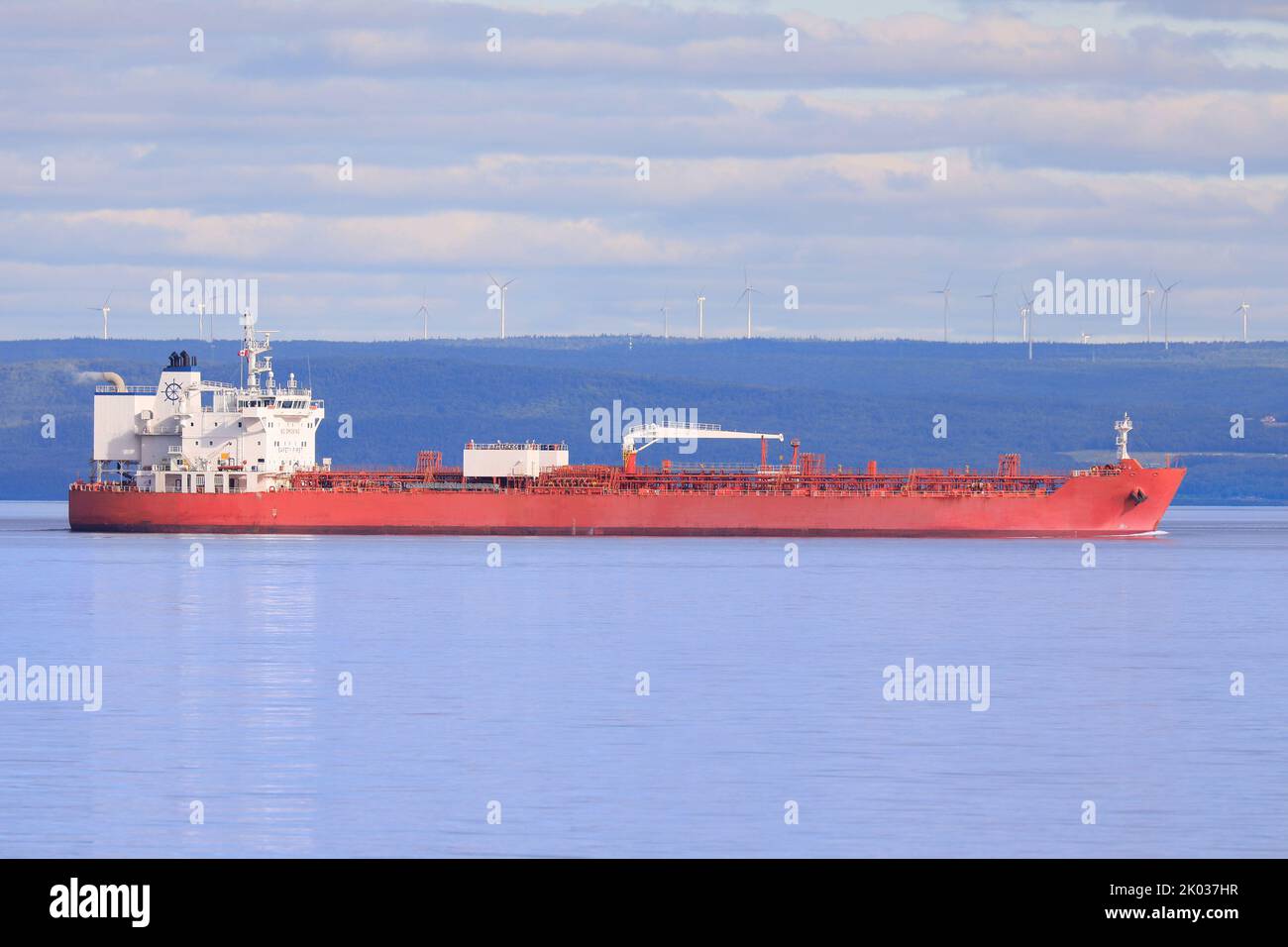 Handelsschiff, das in Quebec, Kanada, auf der Saint Lawrence Mündung mit Windturbinen im Hintergrund segelt Stockfoto