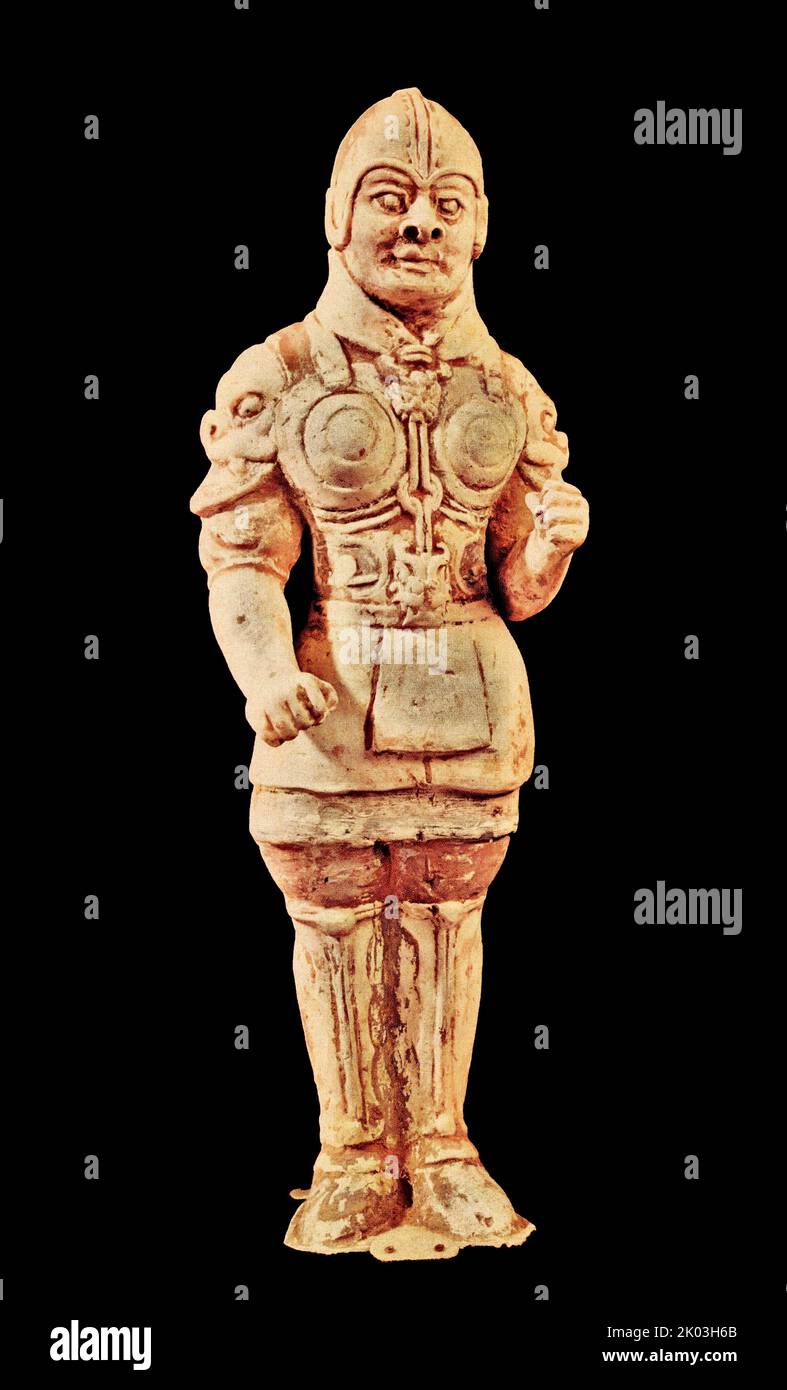 Weiße Figur der Tang-Dynastie, Offizier. Es gibt Spuren gemalter Farben, die aufrecht auf der niedrigen Plattform mit Bestien stehen. Die Figur trägt einen Kuppelhelm, ein Hemd mit hohem Hals und schmalen Ärmeln, einen Mantel aus Rüstung und eine Hose mit schmalen Mäusteln. Die Figur hat prall gefüllte Augen, eine große Nase, einen weiten Mund geschlossen, Koteletten nach links und rechts geteilt, mit einem wilden Gesicht, einem wütenden Blick und ähnelt einem mächtigen Krieger. Diese Form ähnelt den Werken der frühen Tang-Dynastie. Stockfoto Weiße Figur der Tang-Dynastie, Offizier. Es gibt Spuren gemalter Farben, die aufrecht auf der niedrigen Plattform mit Bestien stehen. Die Figur trägt einen Kuppelhelm, ein Hemd mit hohem Hals und schmalen Ärmeln, einen Mantel aus Rüstung und eine Hose mit schmalen Mäusteln. Die Figur hat prall gefüllte Augen, eine große Nase, einen weiten Mund geschlossen, Koteletten nach links und rechts geteilt, mit einem wilden Gesicht, einem wütenden Blick und ähnelt einem mächtigen Krieger. Diese Form ähnelt den Werken der frühen Tang-Dynastie. Stockfoto