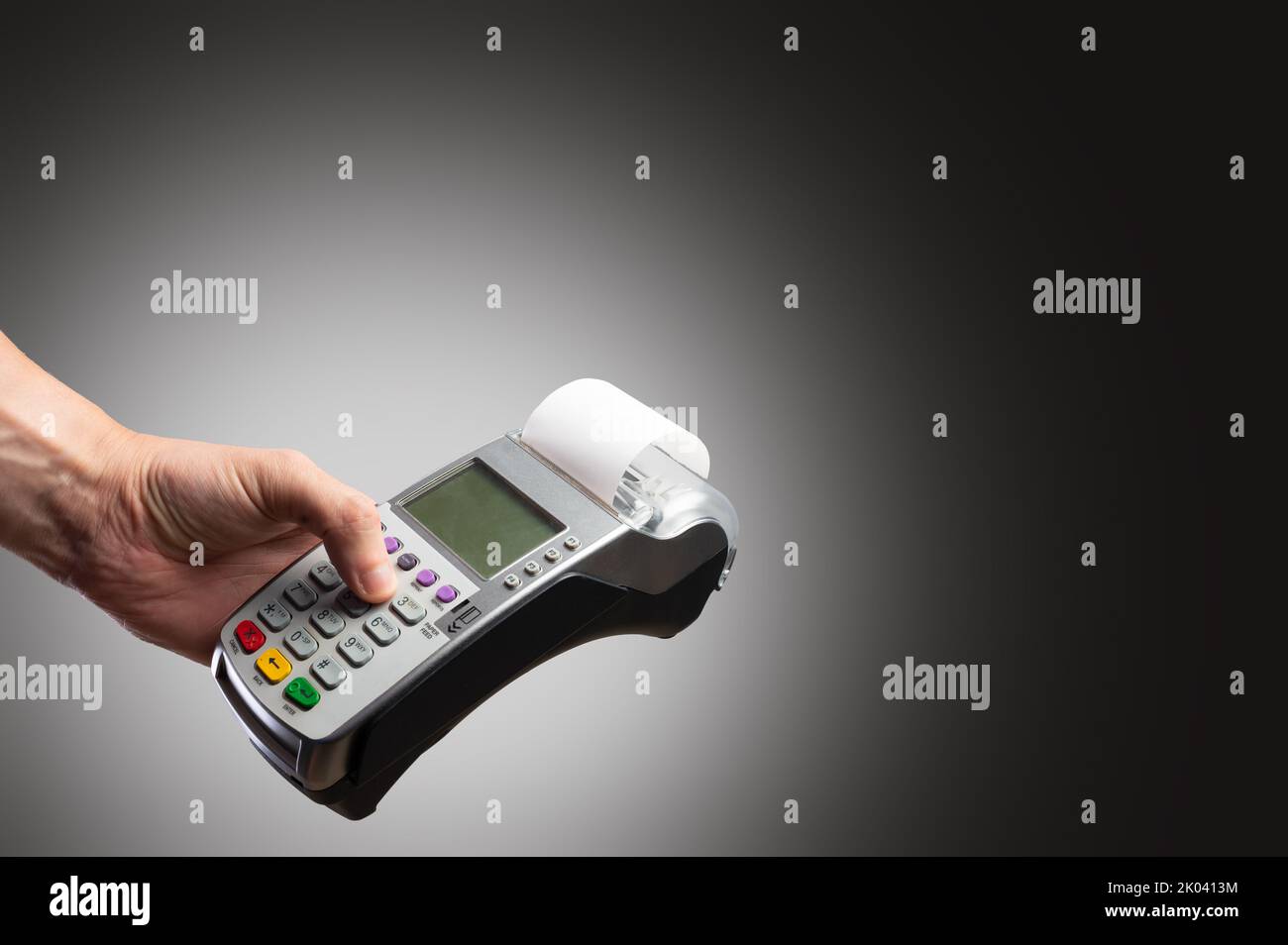 Cash Terminal in der Hand eines Mannes auf grauem Hintergrund. Minimalismus. Handel, Groß- und Einzelhandel, Käufe, Online-Verkäufe und Käufe, Stockfoto