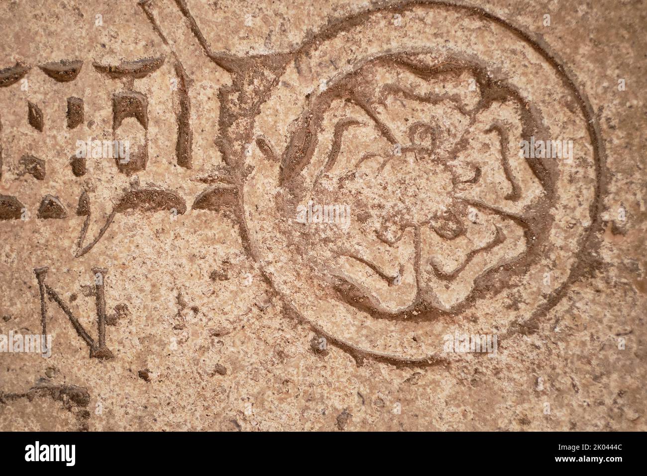 Geschnitztes Symbol einer fünfblättrigen Rose mit einem Globus auf einer Steingrabplatte oder einem Epitaph. Stockfoto