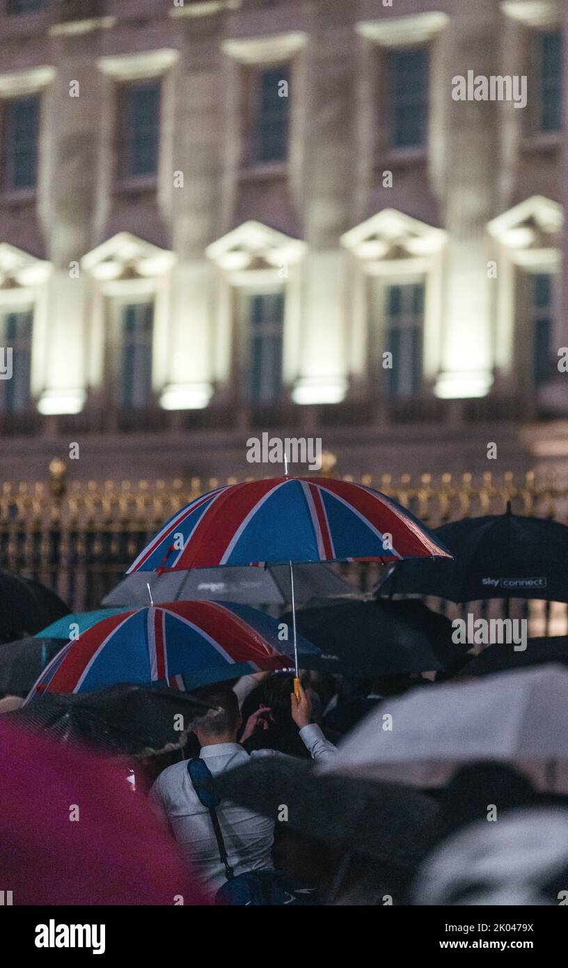 London | UK - 2022.09.08: Menschen trauern und bringen Blumen unter dem Regen vor den Buckingham Palace, nachdem Königin Elizabeth gestorben ist Stockfoto