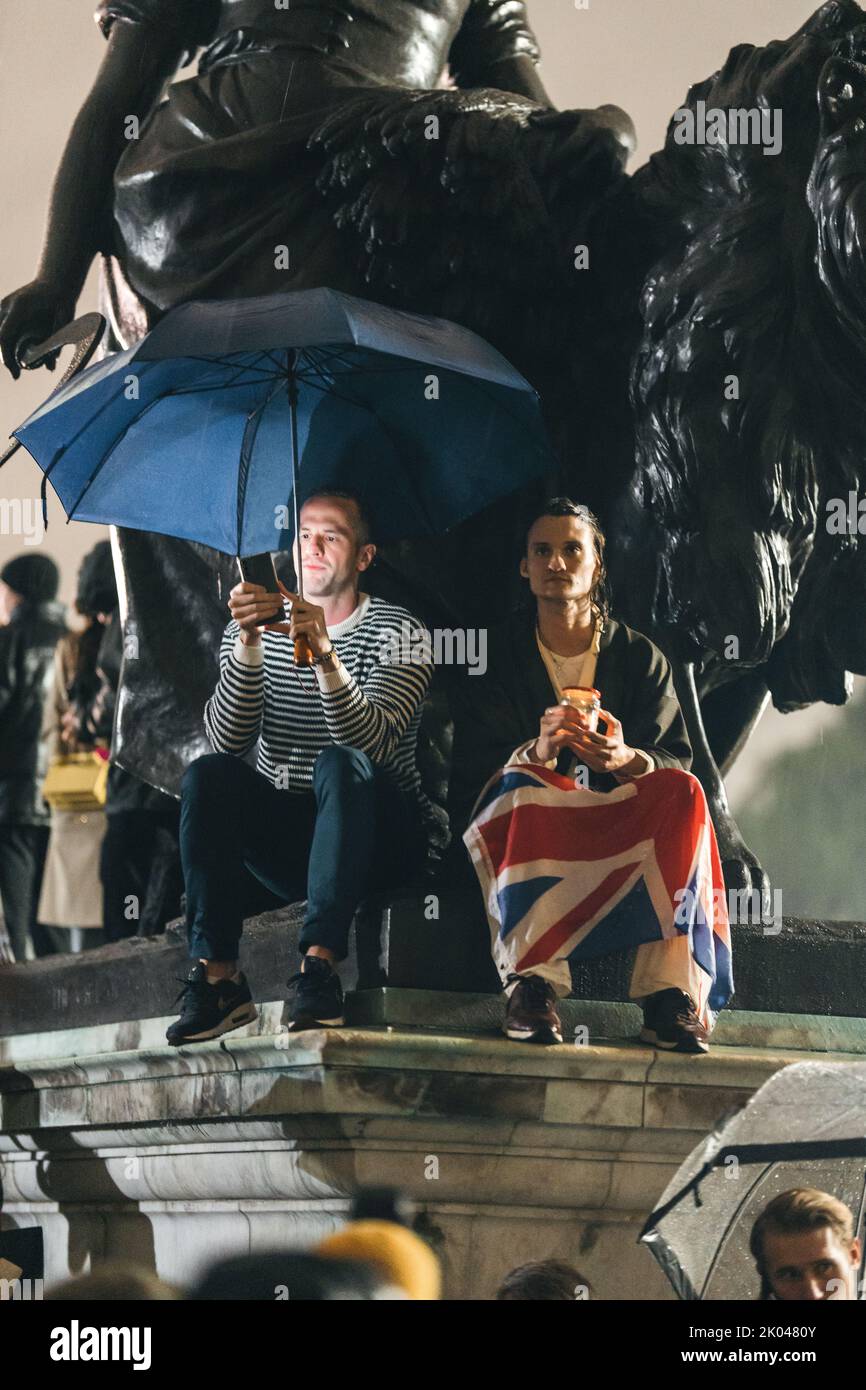 London | UK - 2022.09.08: Menschen trauern und bringen Blumen unter dem Regen vor den Buckingham Palace, nachdem Königin Elizabeth gestorben ist Stockfoto