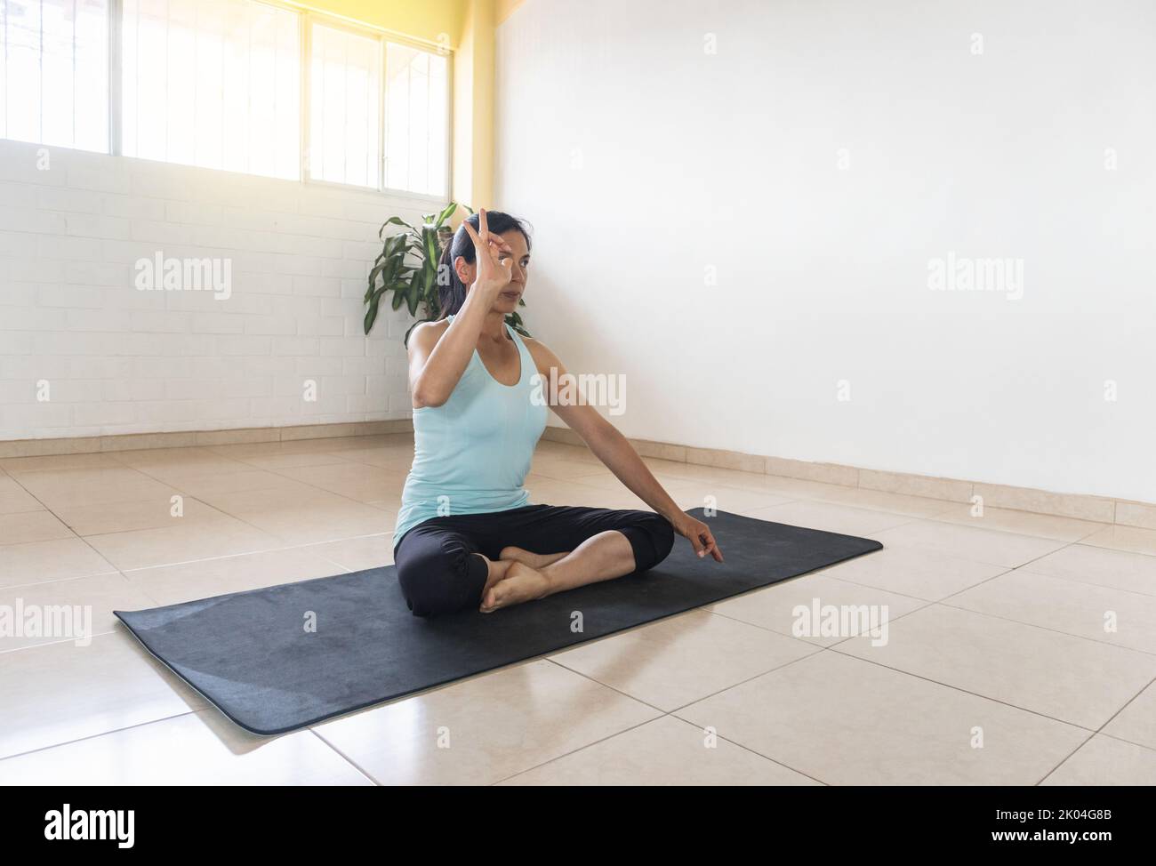 Lateinische Frau, die Audra in Yoga-Haltung zum Atmen gebracht hat Stockfoto